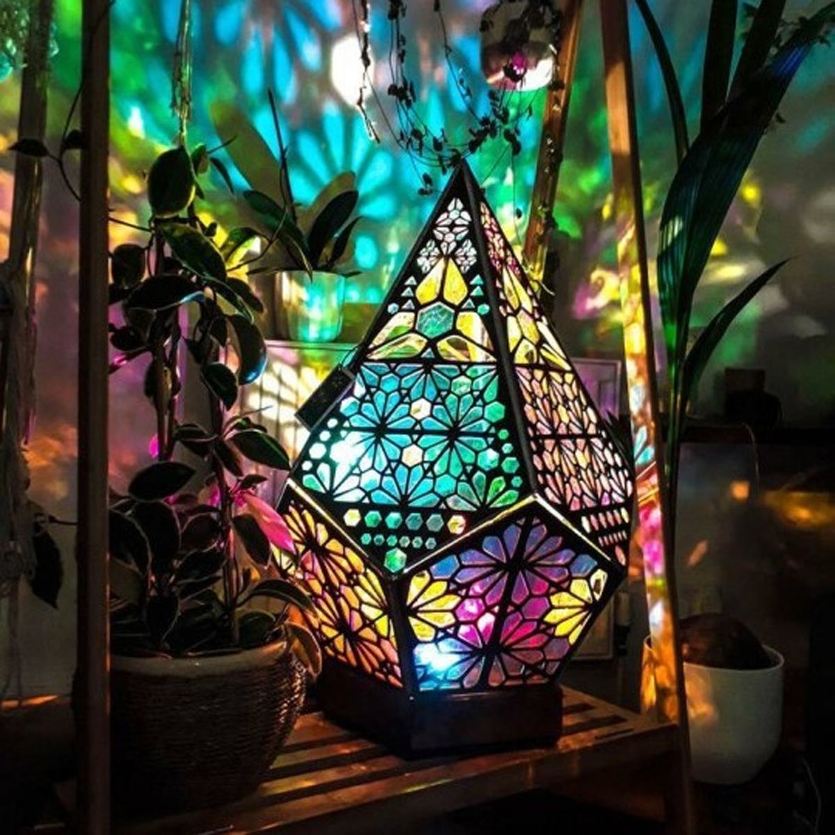 Geometrische Lampe mit bunten Lichtern. Es ist in einem Raum mit Pflanzen und Deko.