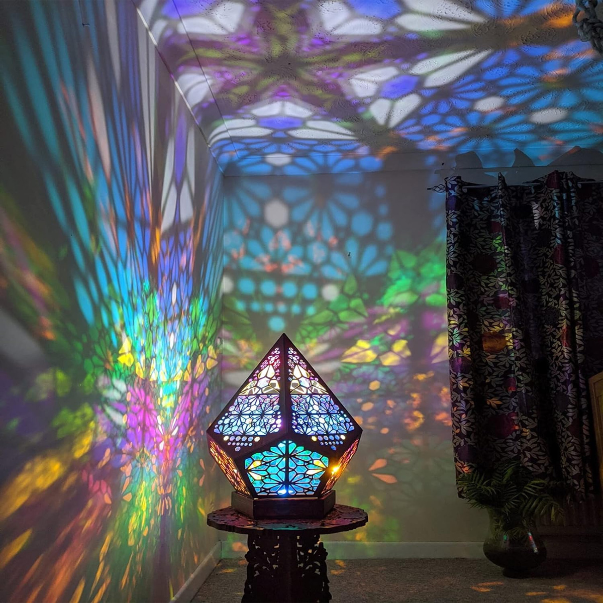 Eine geometrische Lampe projiziert farbenfrohe Lichtmuster auf Wände und Decke.