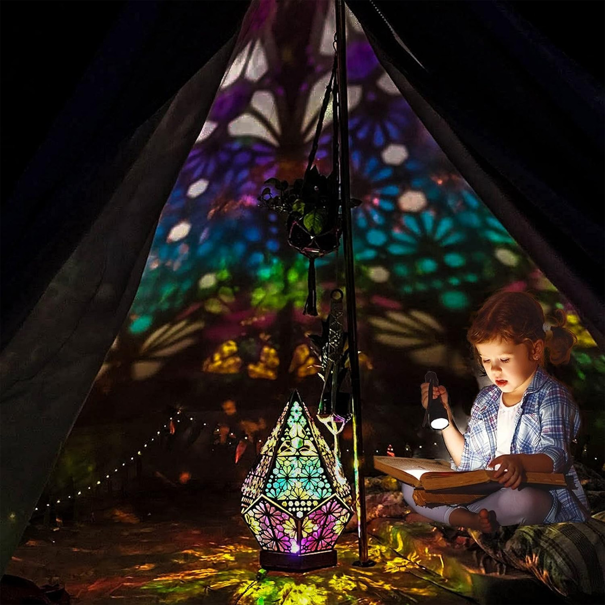 Ein Mädchen liest in einem Zelt, das von einer Lampe beleuchtet wird. Die Lampe projiziert bunte geometrische Muster an die Zeltwände.