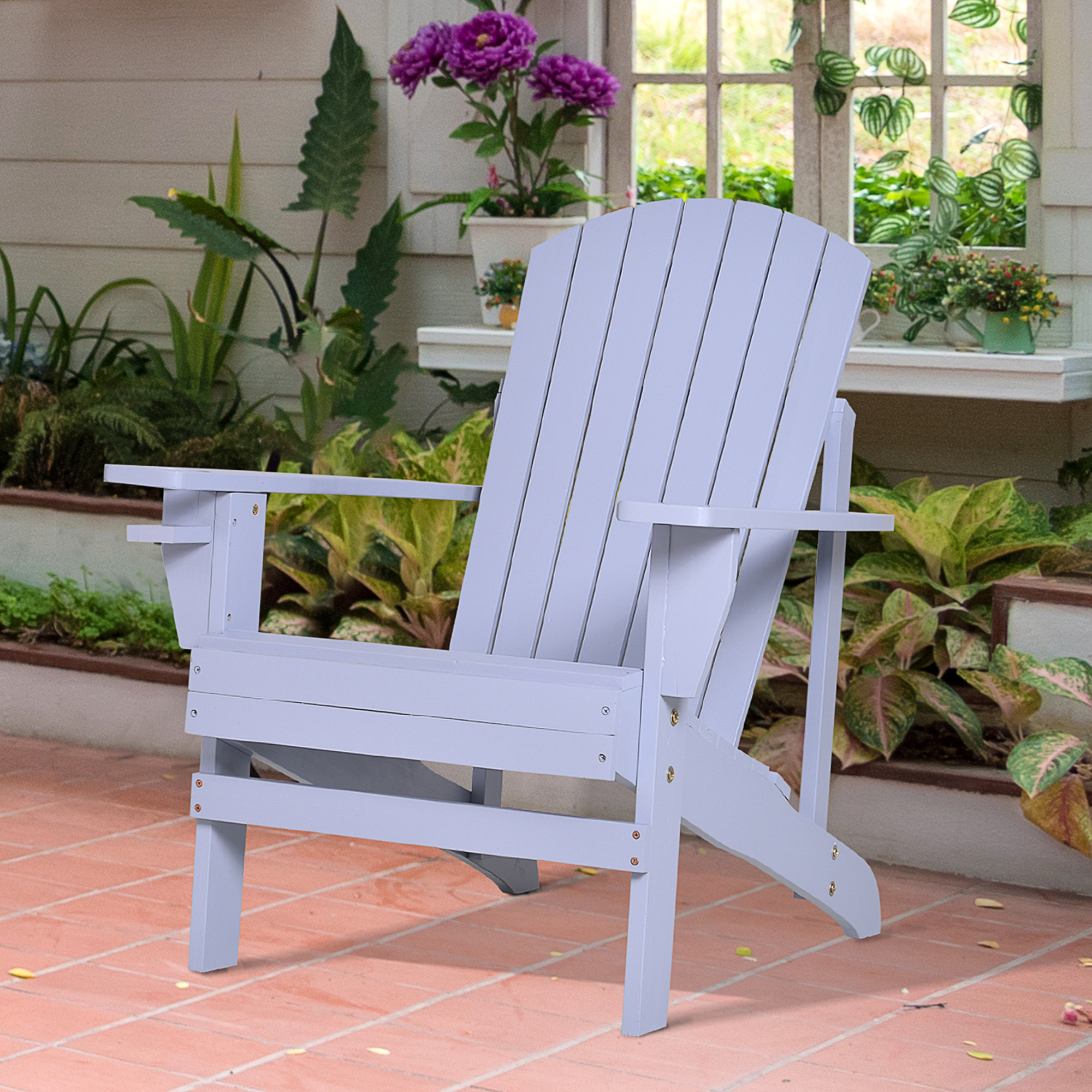 Hellblauer Adirondack-Stuhl aus Holz auf einer Ziegelterrasse. Hintergrund: Pflanzen und eine weiße Wand.