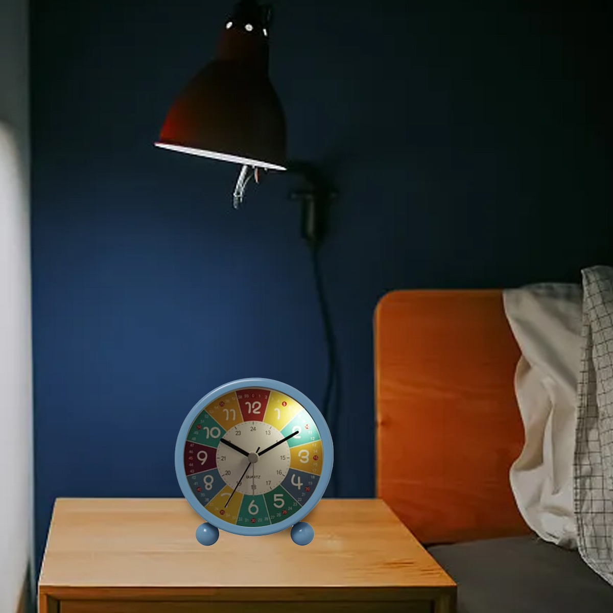 Bunte Uhr auf einem Nachttisch unter einer Lampe, mit blauer Wand im Hintergrund.