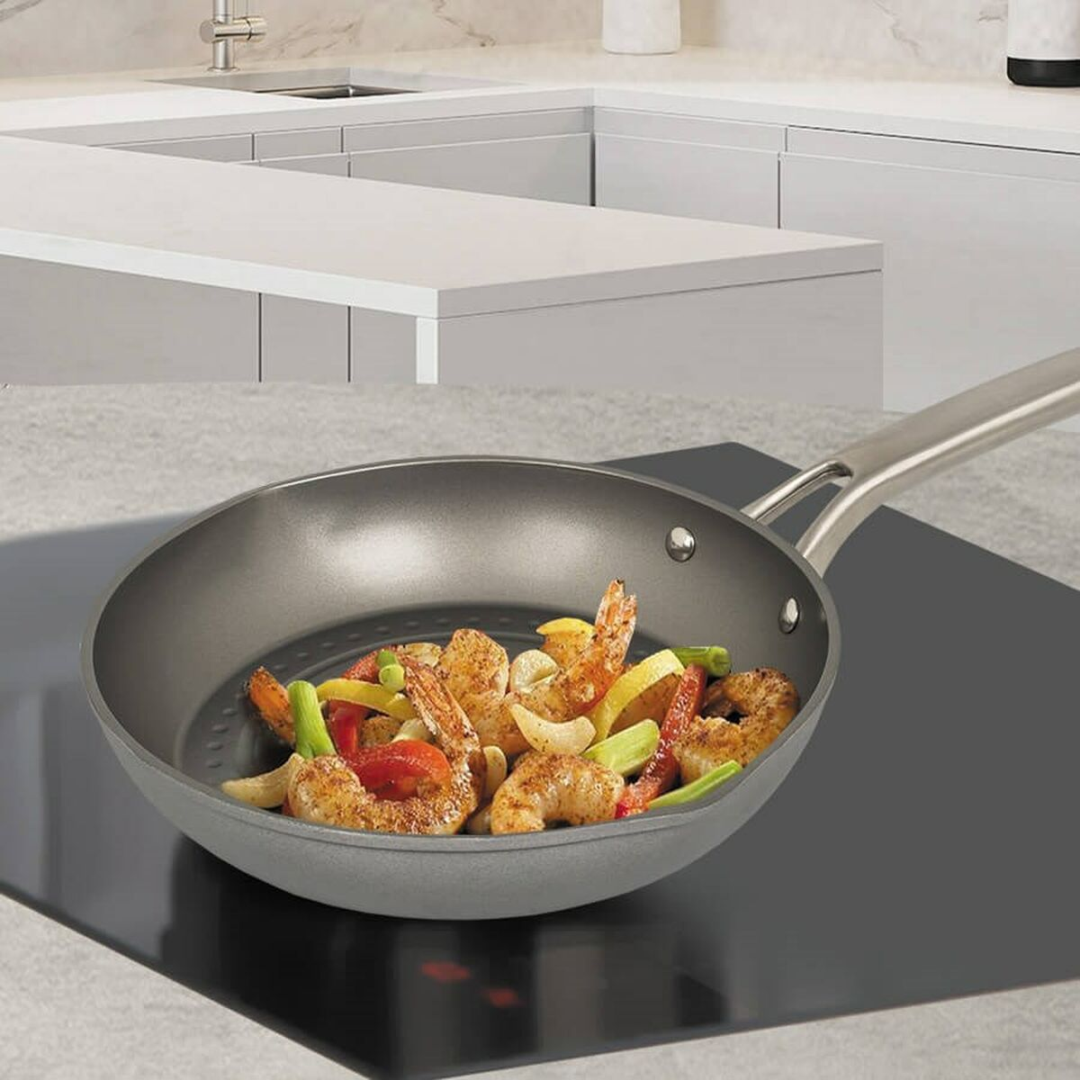 Patelnia z ugotowanymi krewetkami z warzywami na płycie indukcyjnej.
