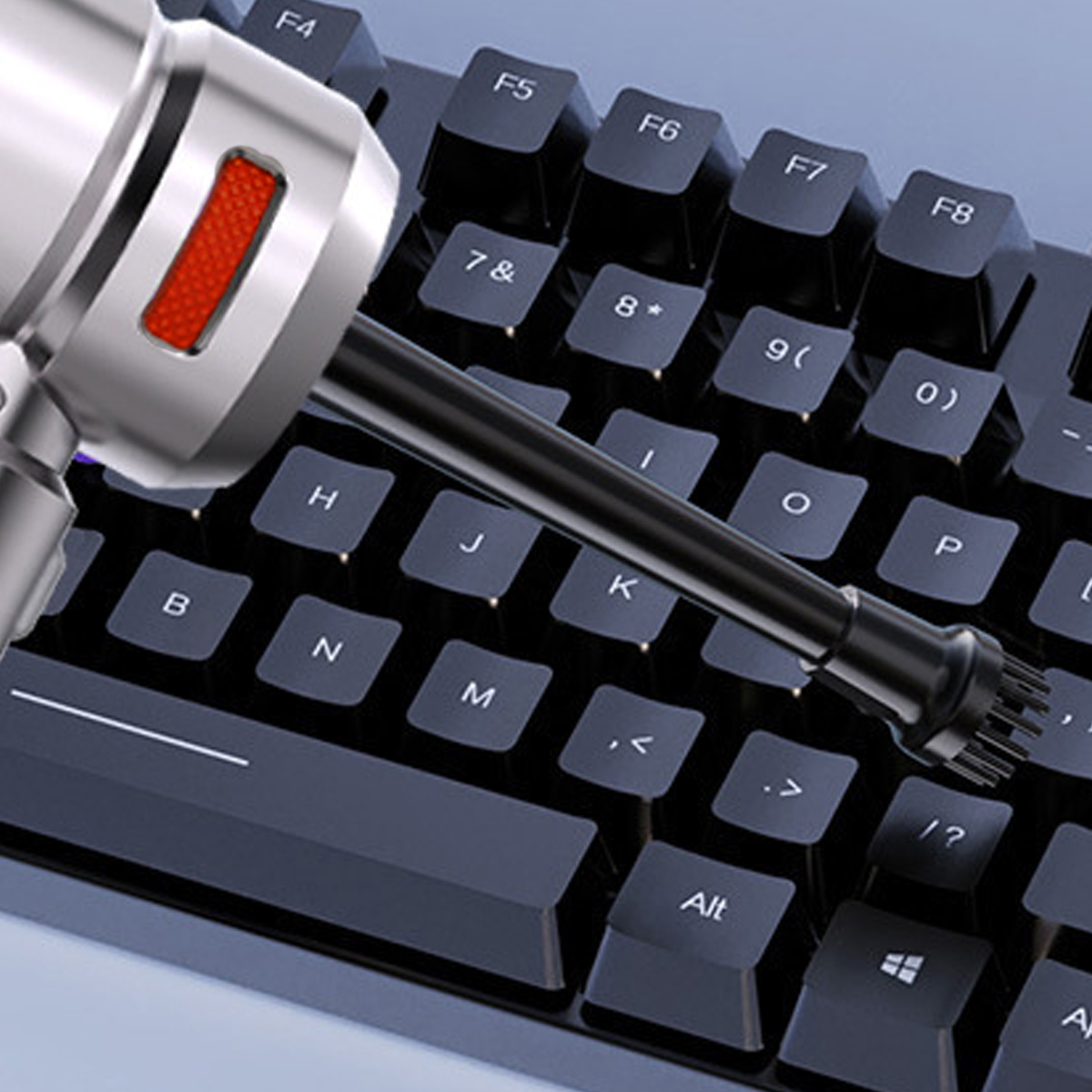 Eine Tastatur mit einem Reinigungswerkzeug. Das Werkzeug ist silberfarben mit einer schwarzen Düse, die um die Tasten reinigt.