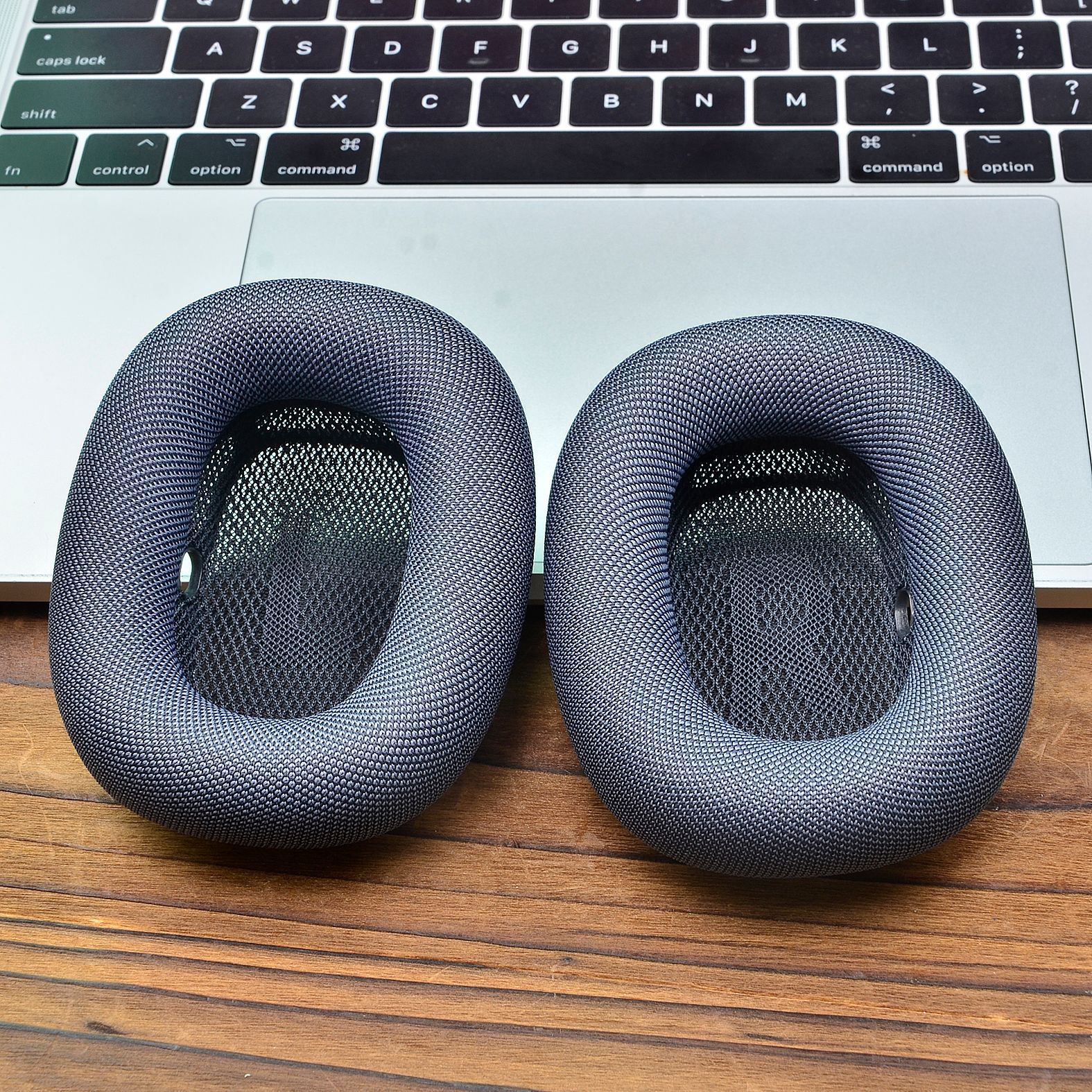 Due cuscinetti grigi per cuffie over-ear sono su una tastiera di un laptop.