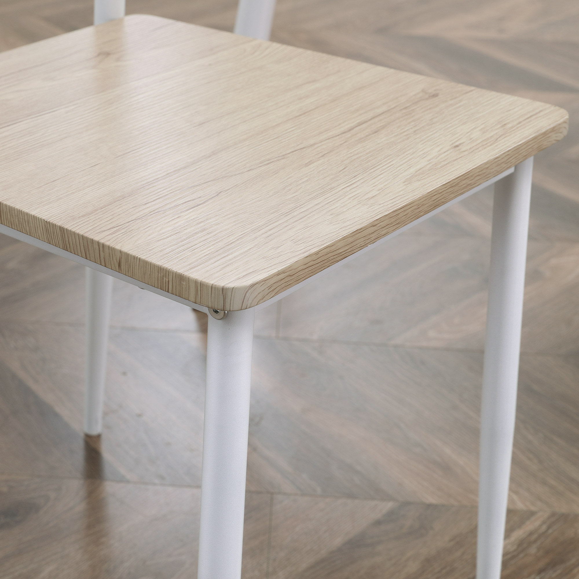 Ein Holztisch mit weißen Beinen wird mit einer Nahaufnahme der Ecke gezeigt.