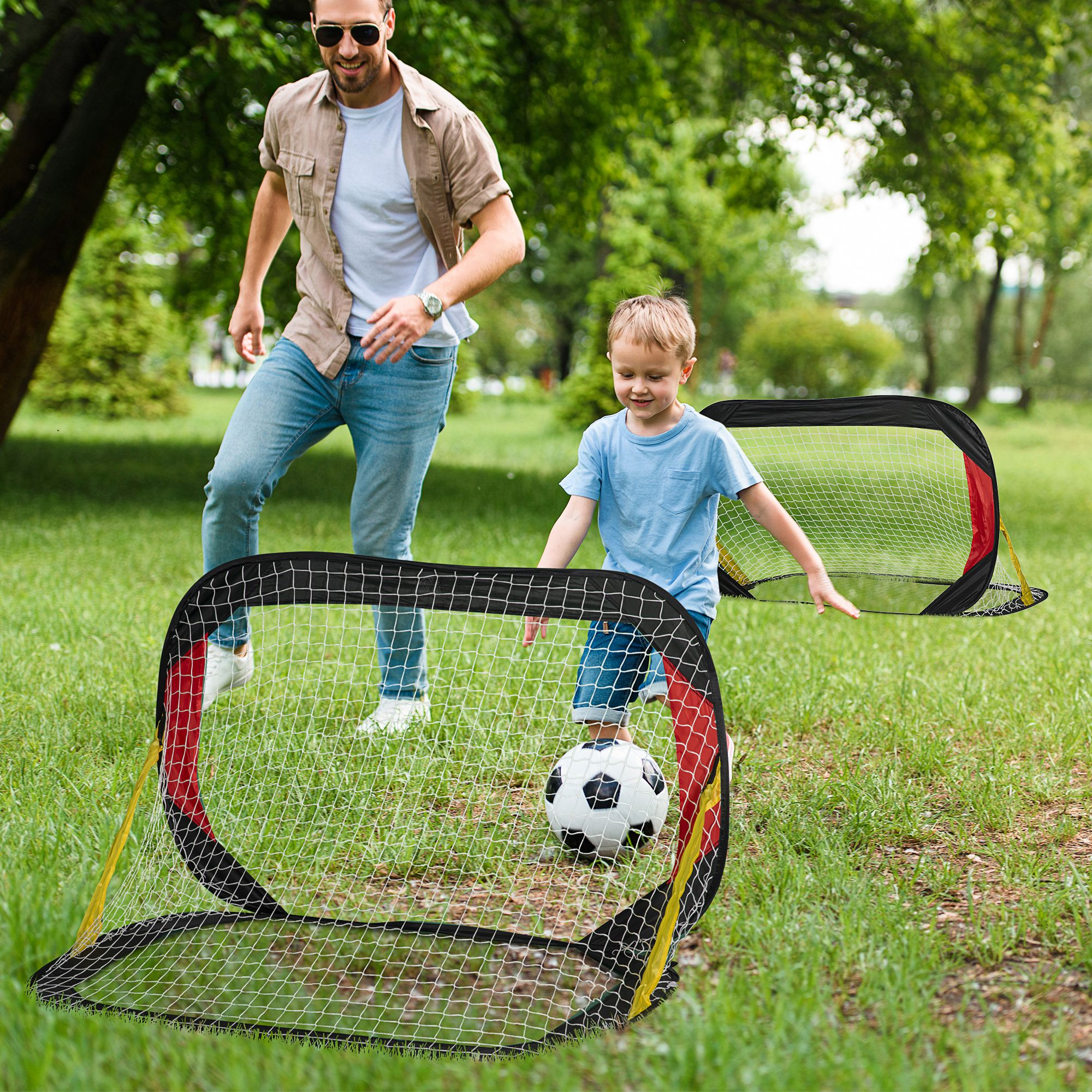 Vater und Sohn spielen Fußball. Ein Tor und ein Ball im Gras an einem sonnigen Tag.