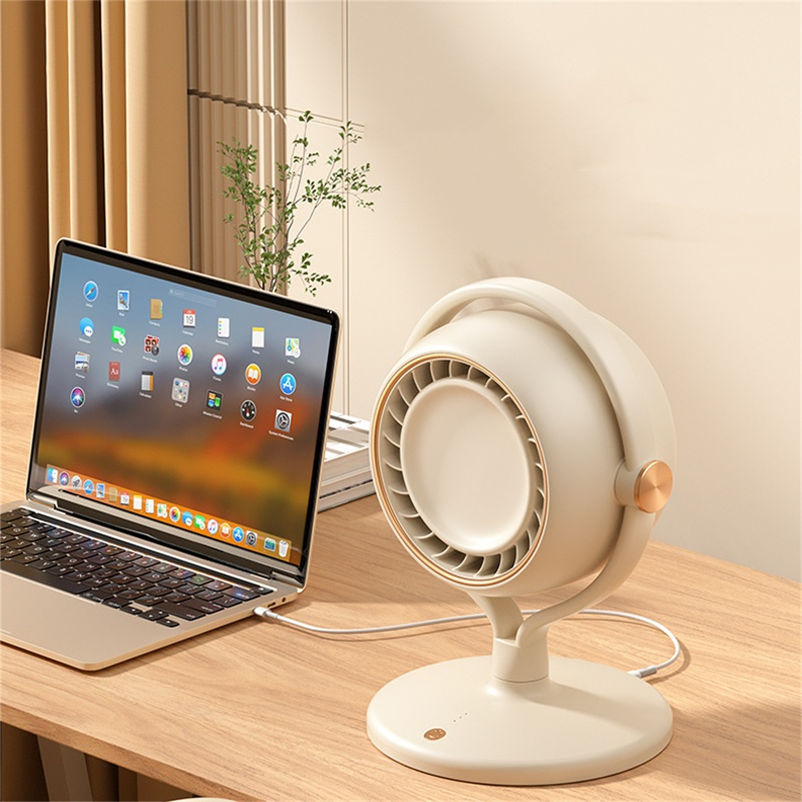 Ein beiger Ventilator neben einem Laptop auf einem Holzschreibtisch. Der Lüfter hat einen goldenen Ring um den Luftauslass. Weißes Kabel.