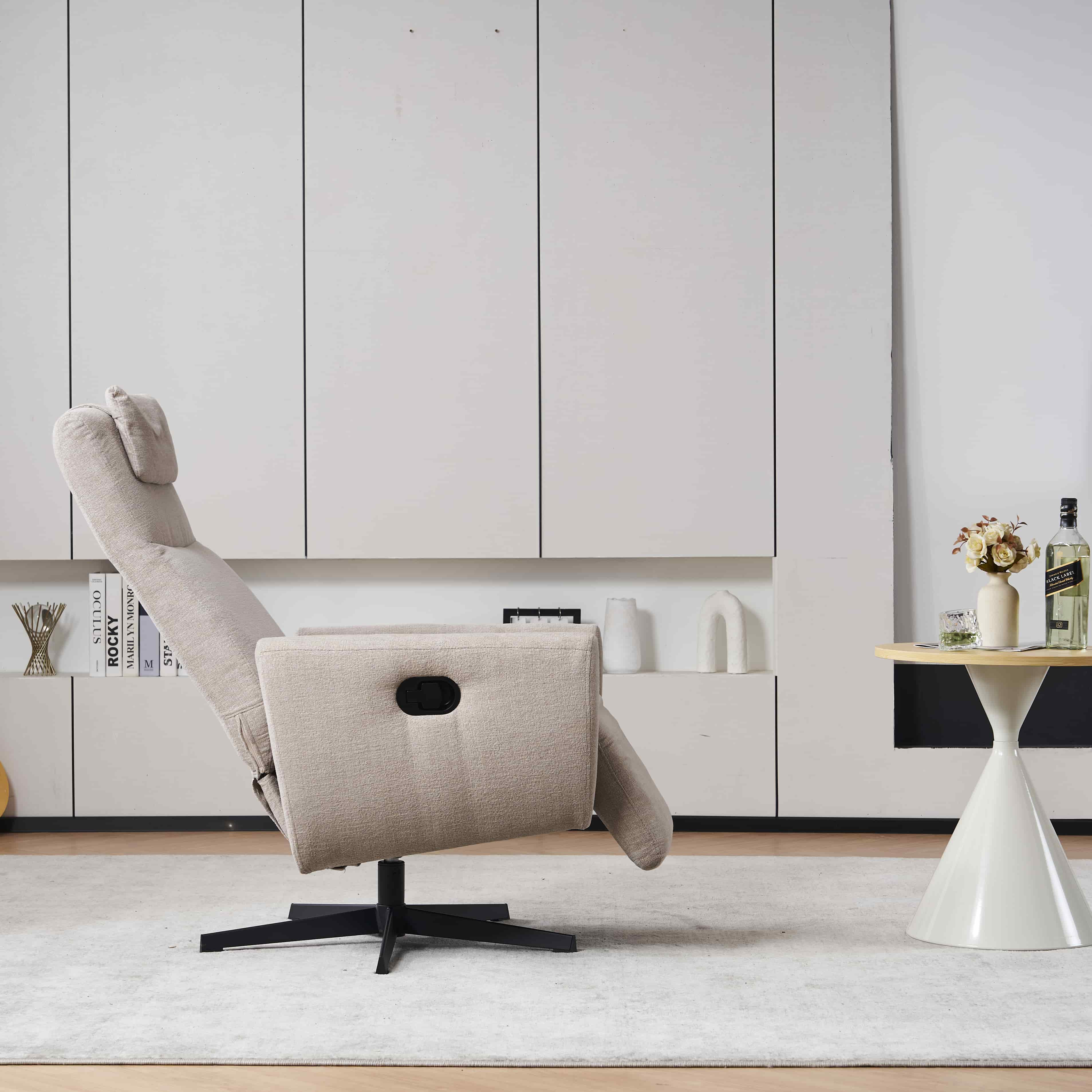 Beiger Relaxsessel mit schwarzem Fußgestell, vor einer weißen Wand mit kleinem Tisch und Dekoration.