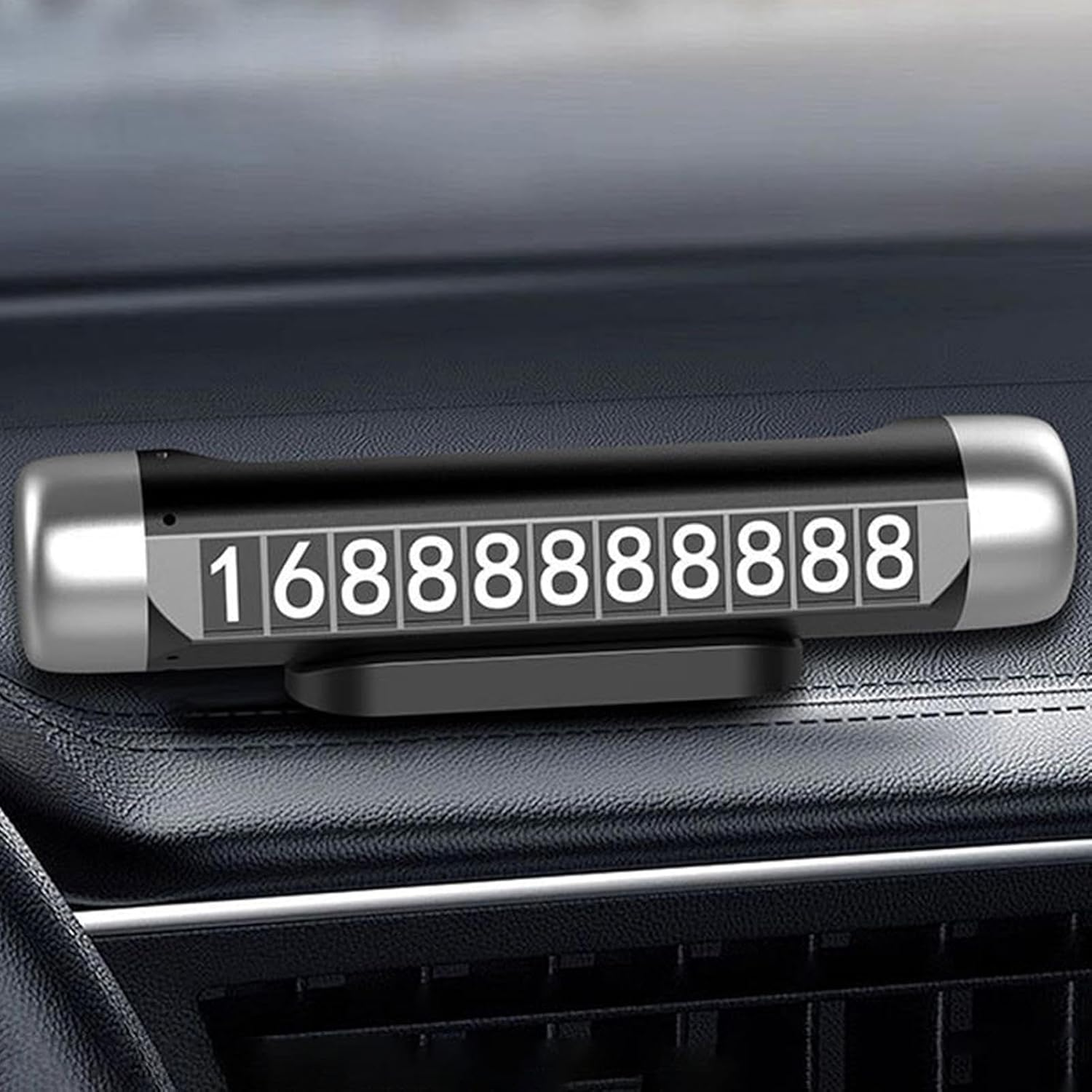 Eine Kfz-Telefonnummernanzeige mit silbernem Rahmen und der Nummer 16888888888. Auf einem Armaturenbrett.