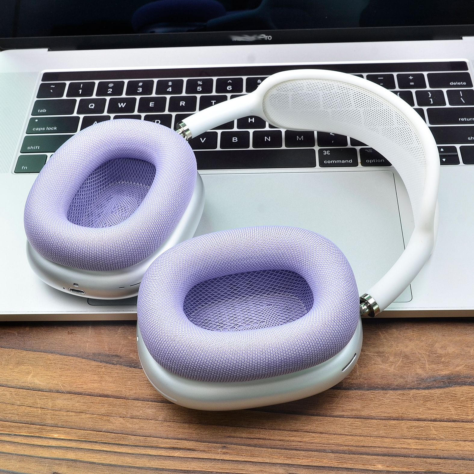 Cuffie bianche e viola sulla tastiera di un laptop. Le cuffie sono sopra le orecchie.