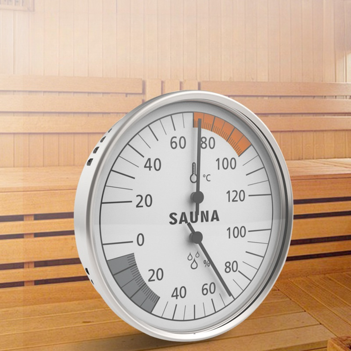 Ein runder Sauna-Thermometer zeigt 80 Grad Celsius und 60 % Luftfeuchtigkeit an. Es befindet sich auf einem Holzgrund.