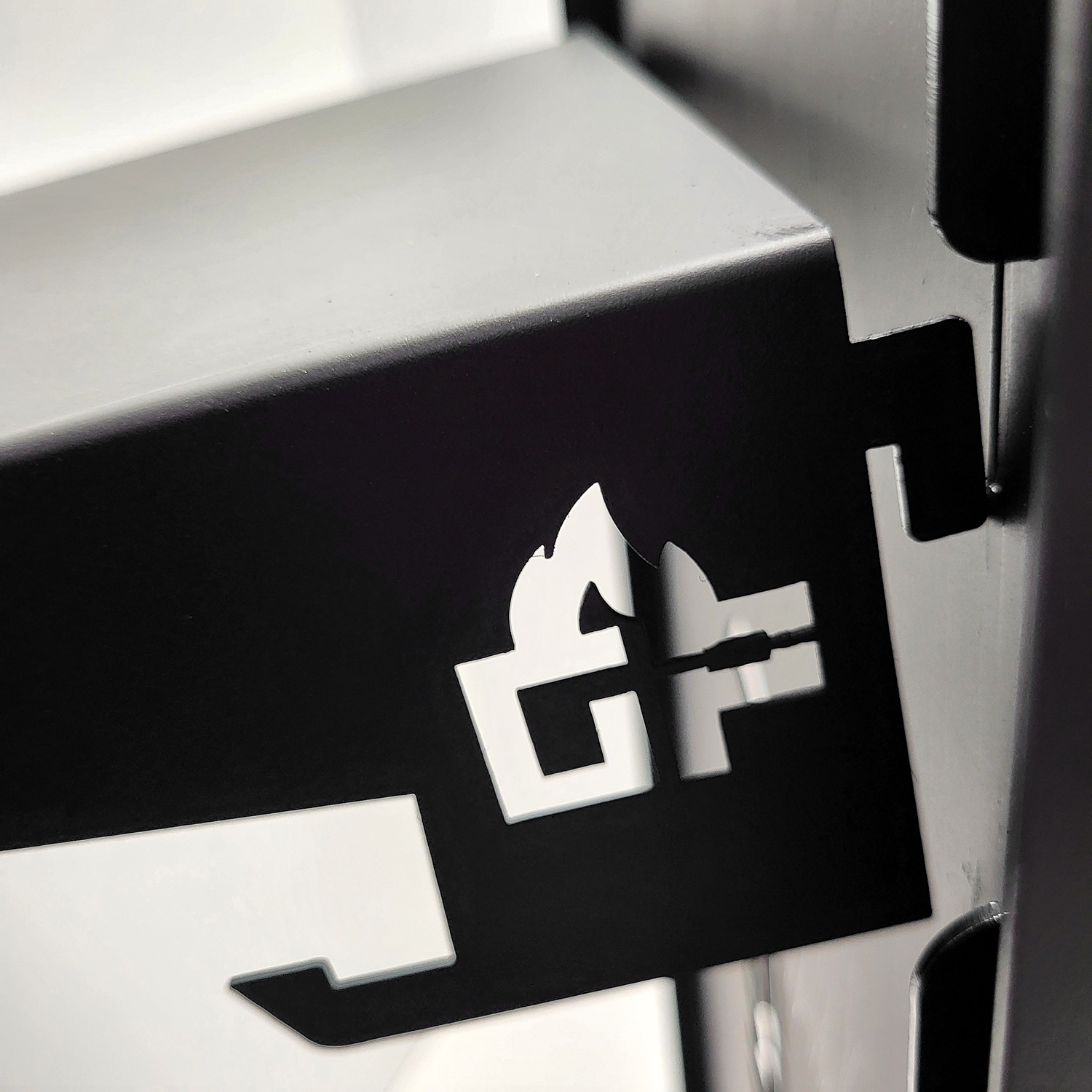 Nahaufnahme einer schwarzen Metallstruktur mit dem GF-Logo in Weiß. Das Logo ist stilisiert.