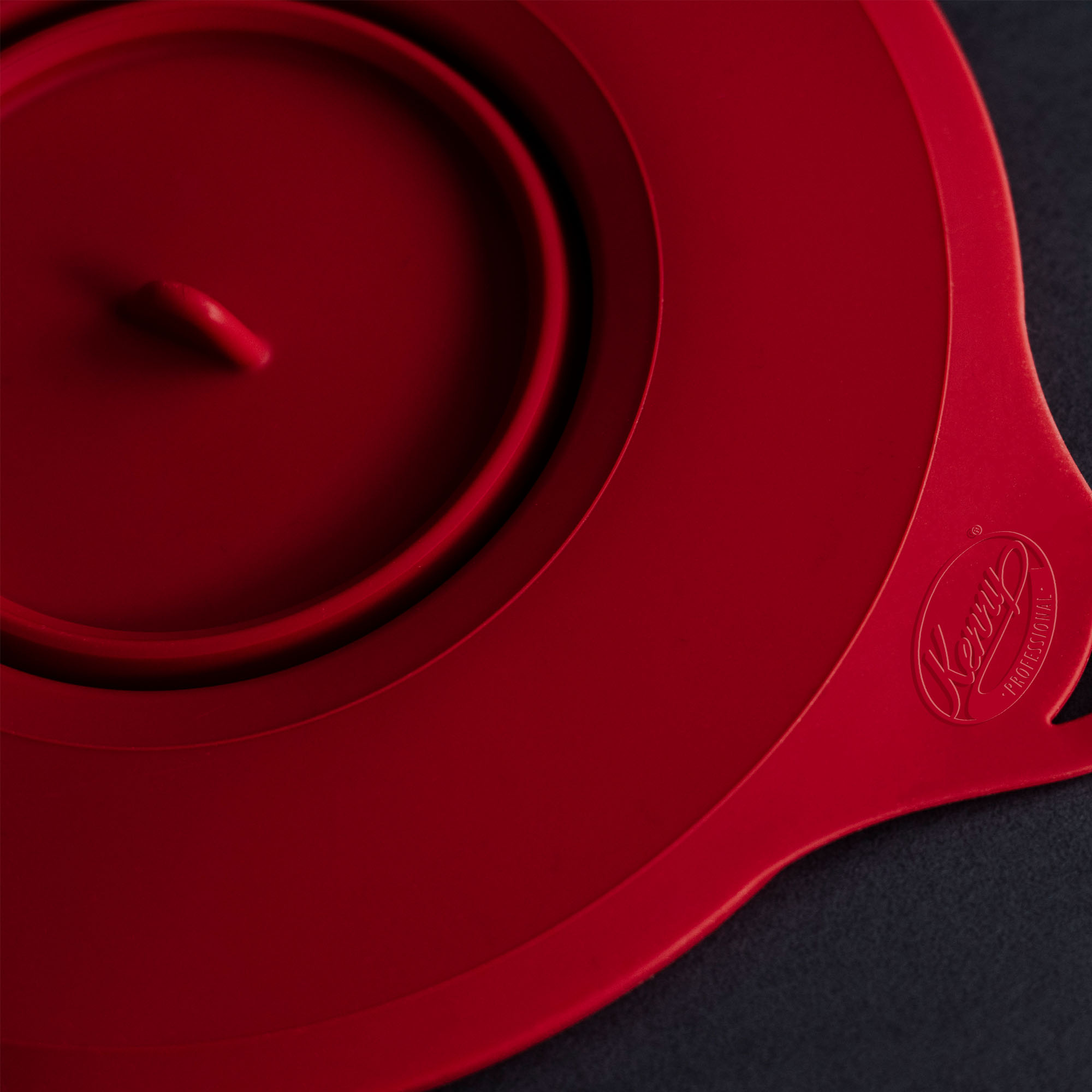 Roter Silikondeckel mit Deckelgriff. Dunkler Hintergrund.
