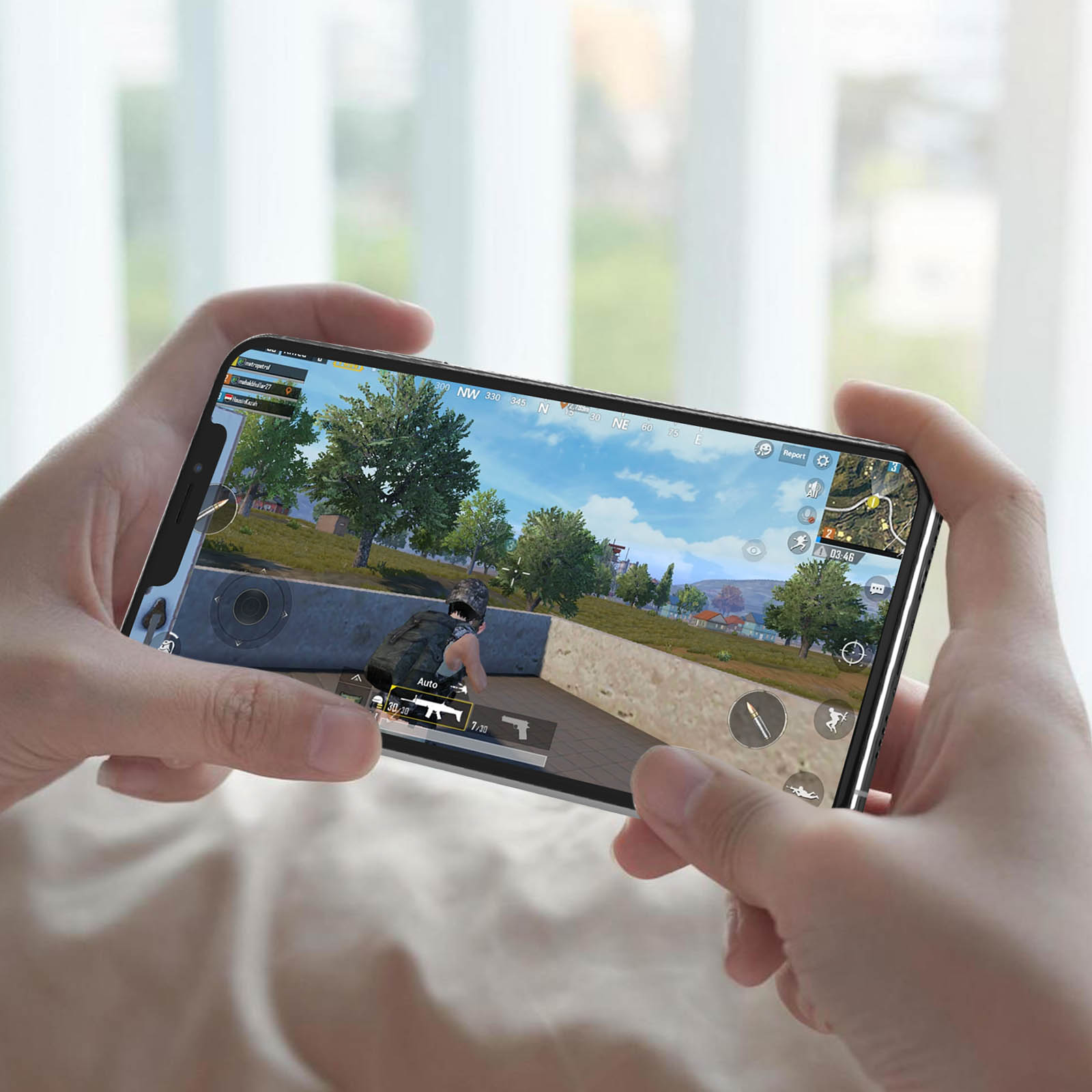 Una persona tiene in mano uno smartphone che gioca a un videogioco. La scena del gioco mostra una foresta.