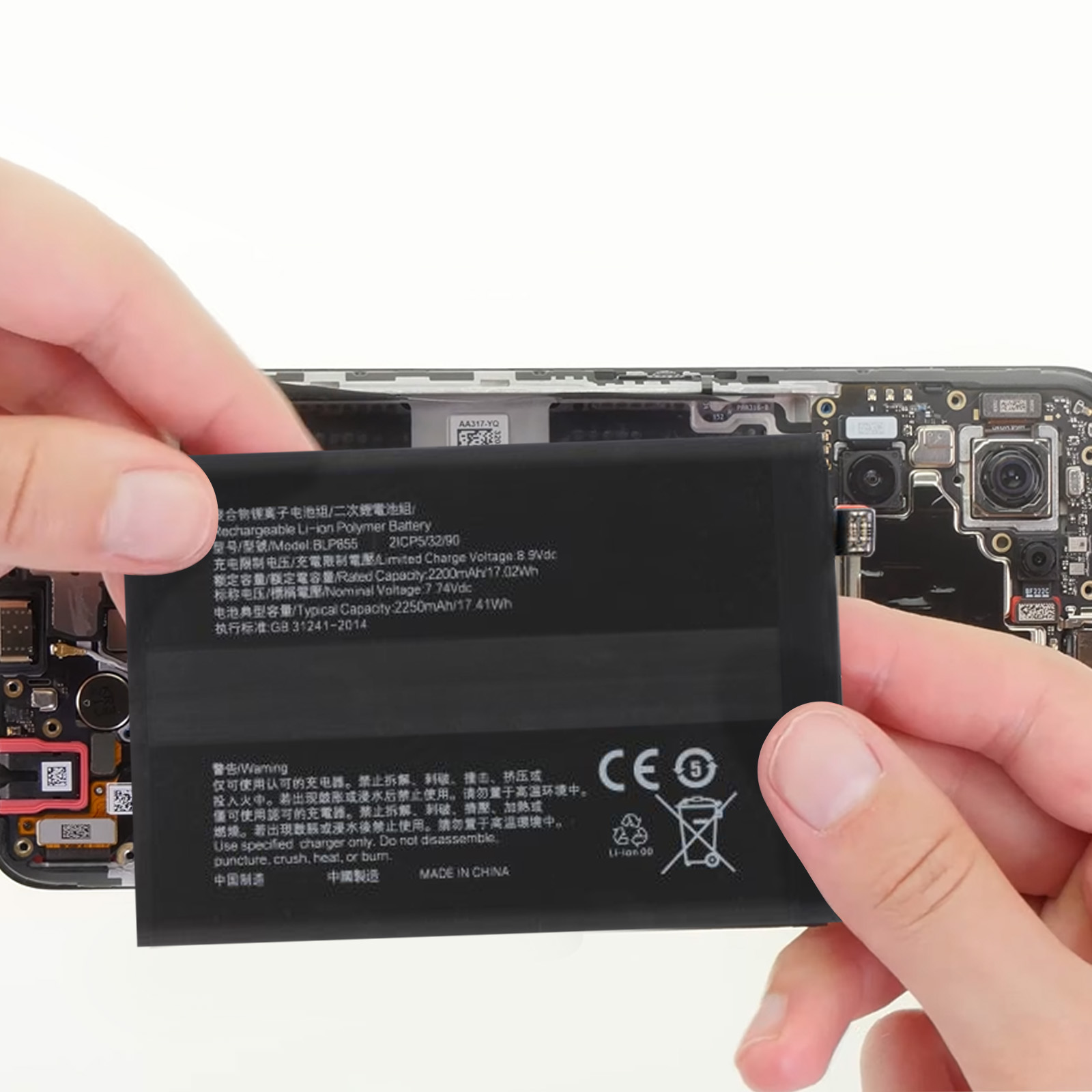 Una batteria viene tenuta, con testo e simboli visibili. Una mano tiene l'oggetto rettangolare nero.