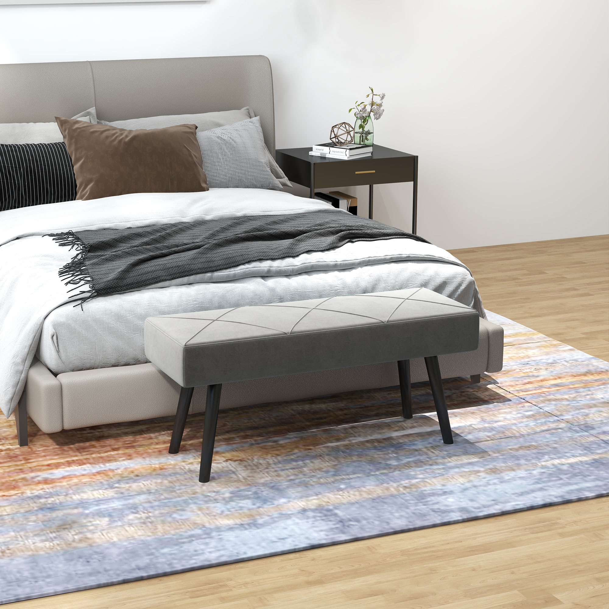 Schlafzimmer-Szene mit einer Bank vor dem Bett, einem Teppich und einem Nachttisch mit Lampe.