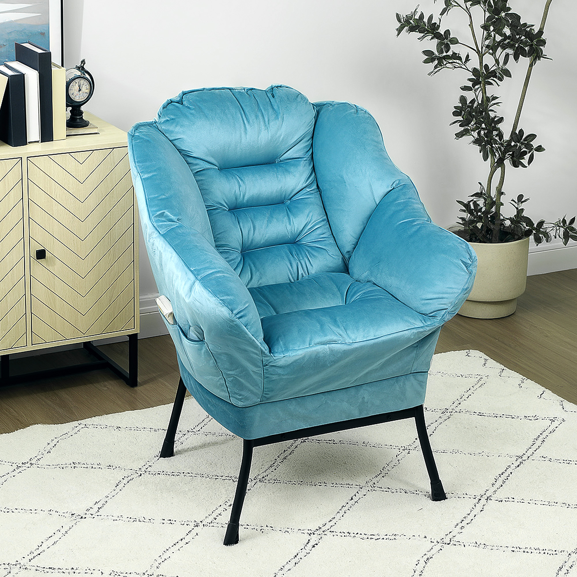 Blauer Sessel auf einem weißen Teppich, mit Schrank und Pflanze im Hintergrund.