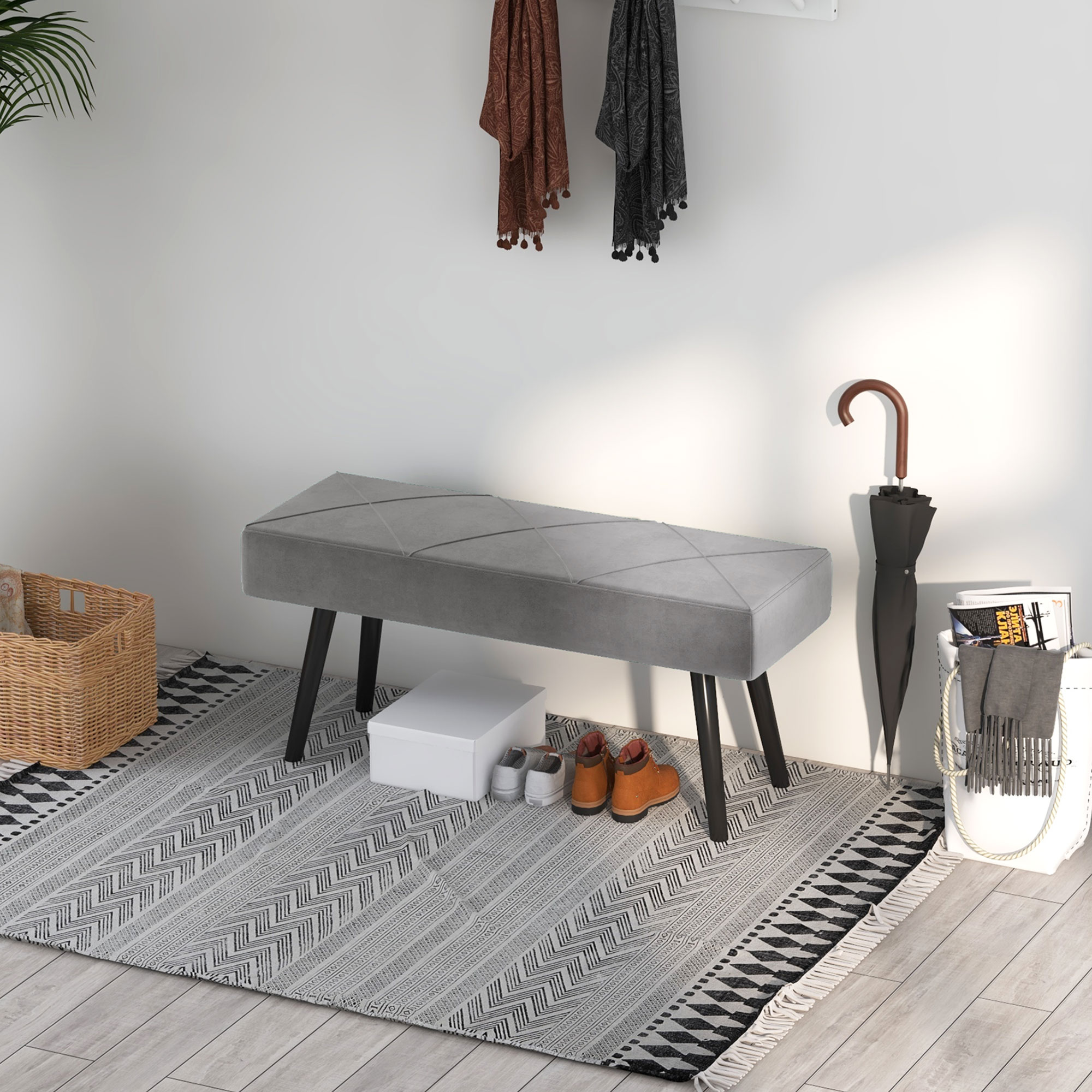 Graue Bank mit schwarzen Beinen, Schuhe darunter. Teppich mit geometrischem Muster.