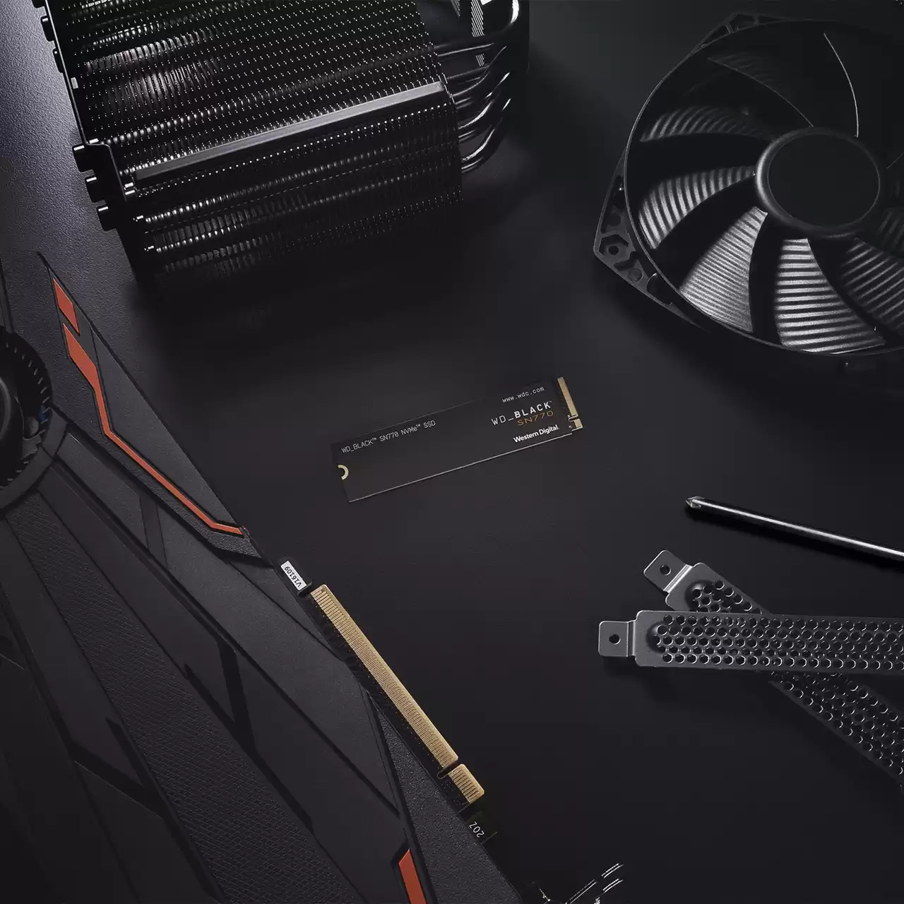 Configurazione tech nera su superficie nera con SSD, ventola, GPU.
