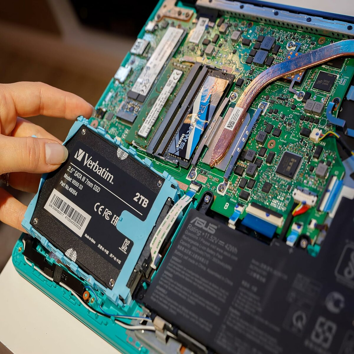 Wewnętrzne komponenty laptopa. Instalacja dysku SSD. Zielona płyta główna z różnymi układami i komponentami.