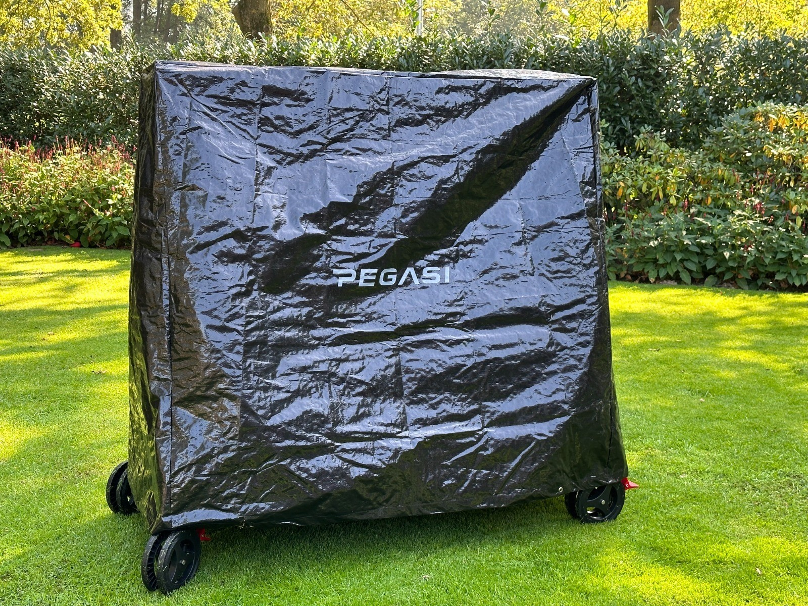 Black cover on a table tennis table in a green lawn.
