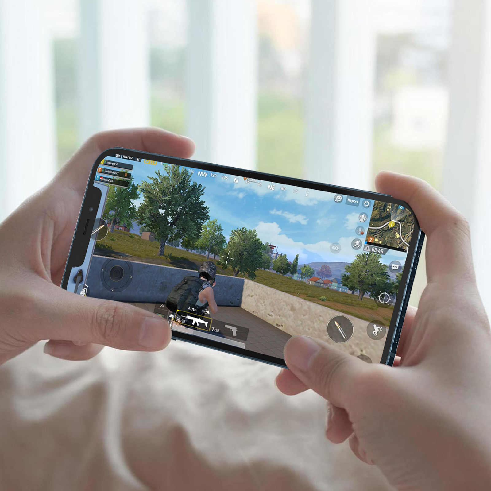 Mani che tengono un telefono, che mostrano una persona che gioca a un videogioco con un paesaggio. Lo schermo di gioco è visibile.