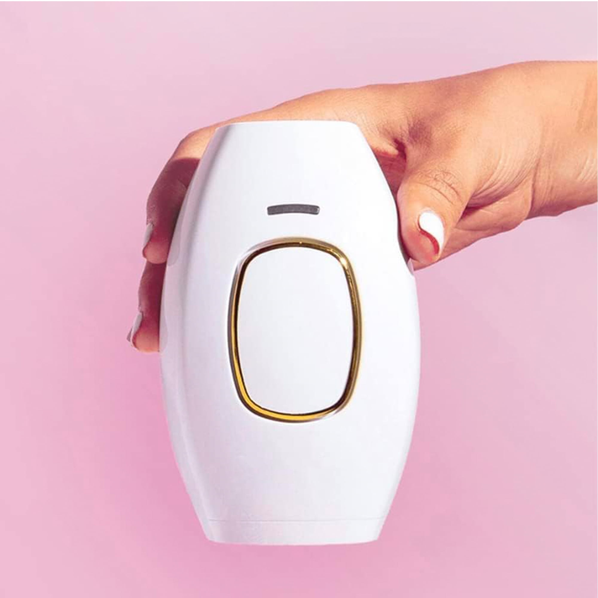 Weißes Haarentfernungsgerät, gehalten von einer Hand. Pinker Hintergrund. Goldakzente.