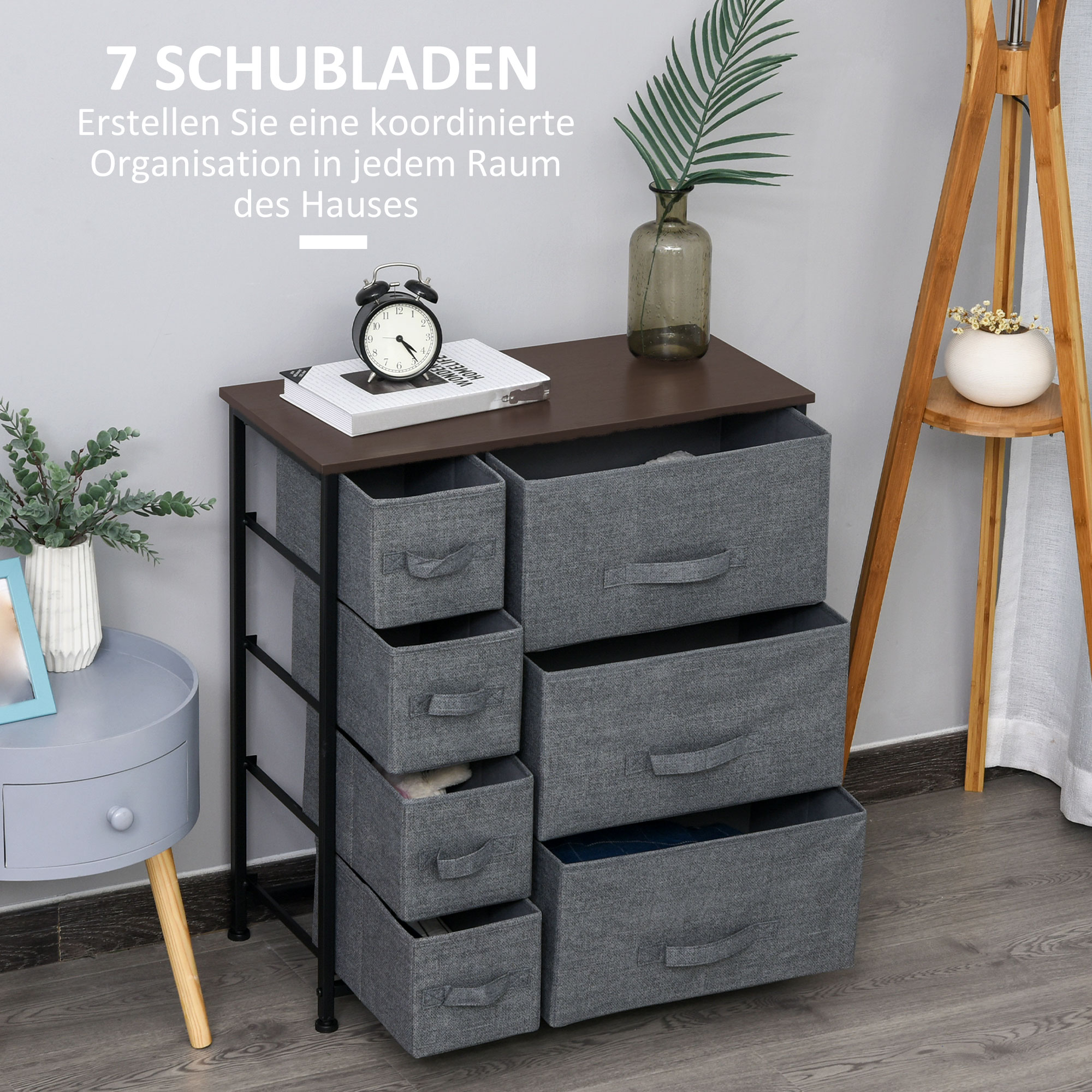 Eine graue Kommode mit 7 Schubladen, bedeckt mit dunklem Holz, und ein kleiner Dekotisch.