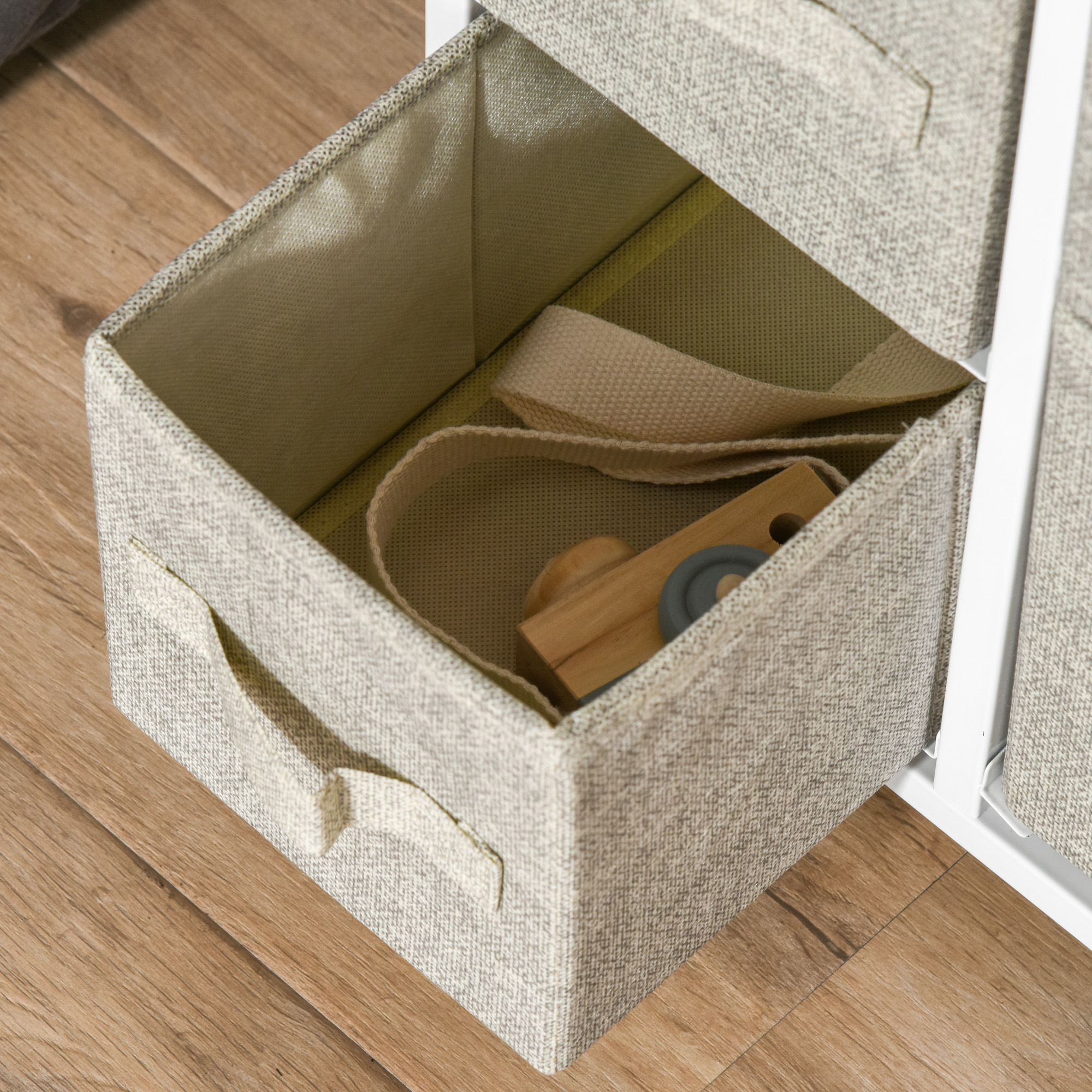 Offene Schublade mit hölzerner Spielzeugkamera. Die Schublade ist in einem beigefarbenen Stoffschrank.