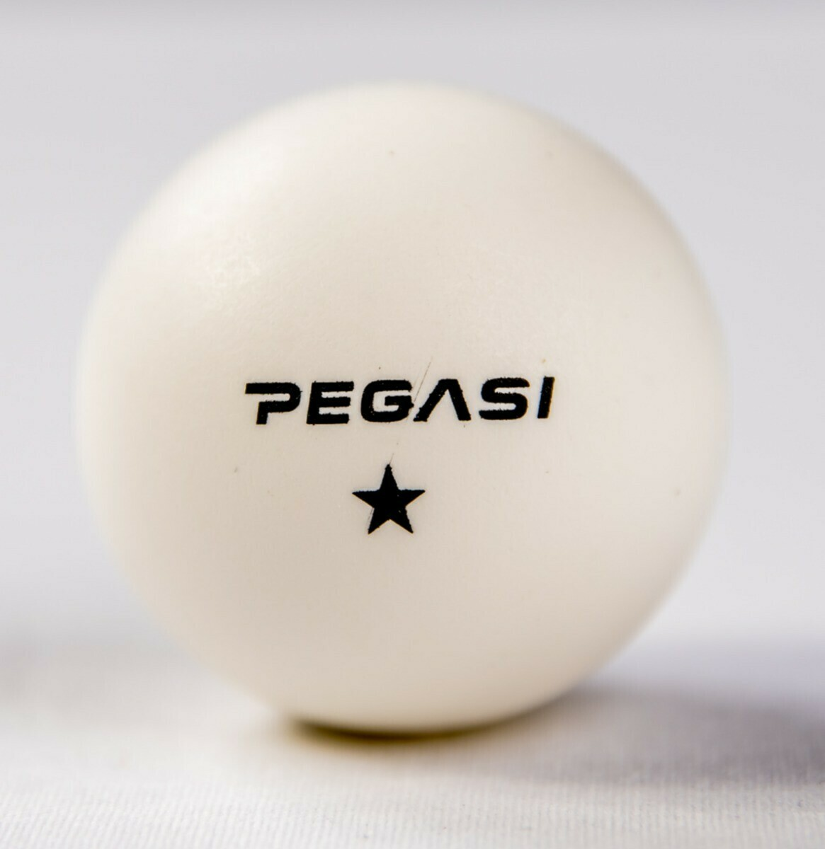 A white table tennis ball with the brand 'PEGASI' and a star symbol printed on it.