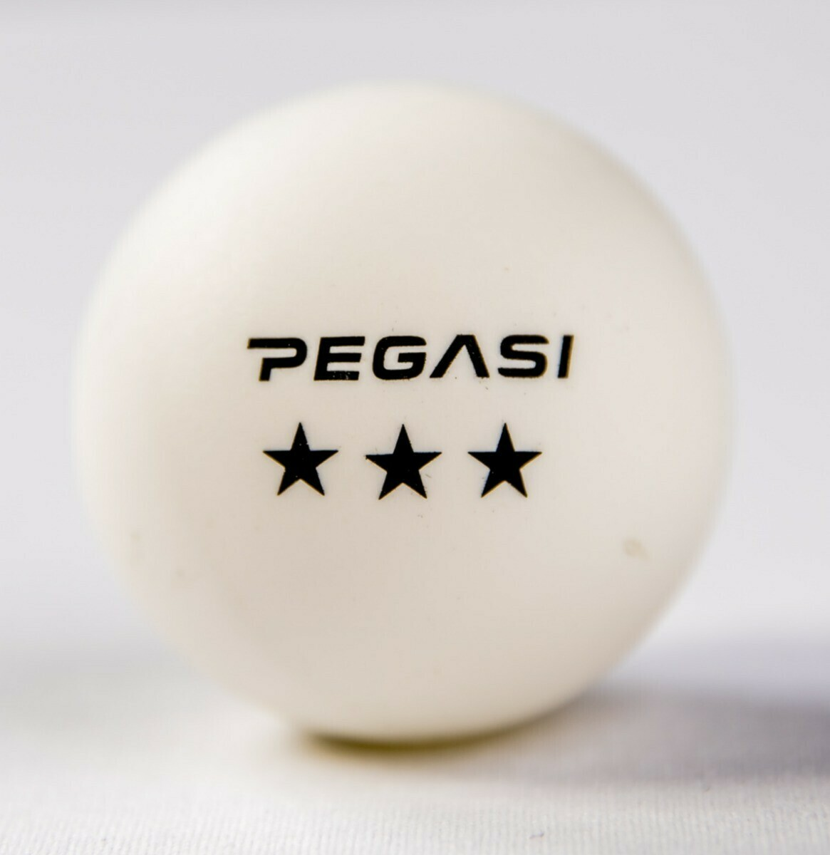White ping pong ball with black 'PEGASI' text and three stars.