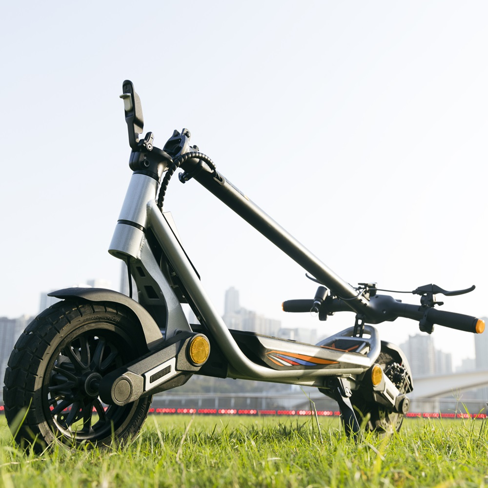 Scooter elettrico sull'erba, città sullo sfondo.