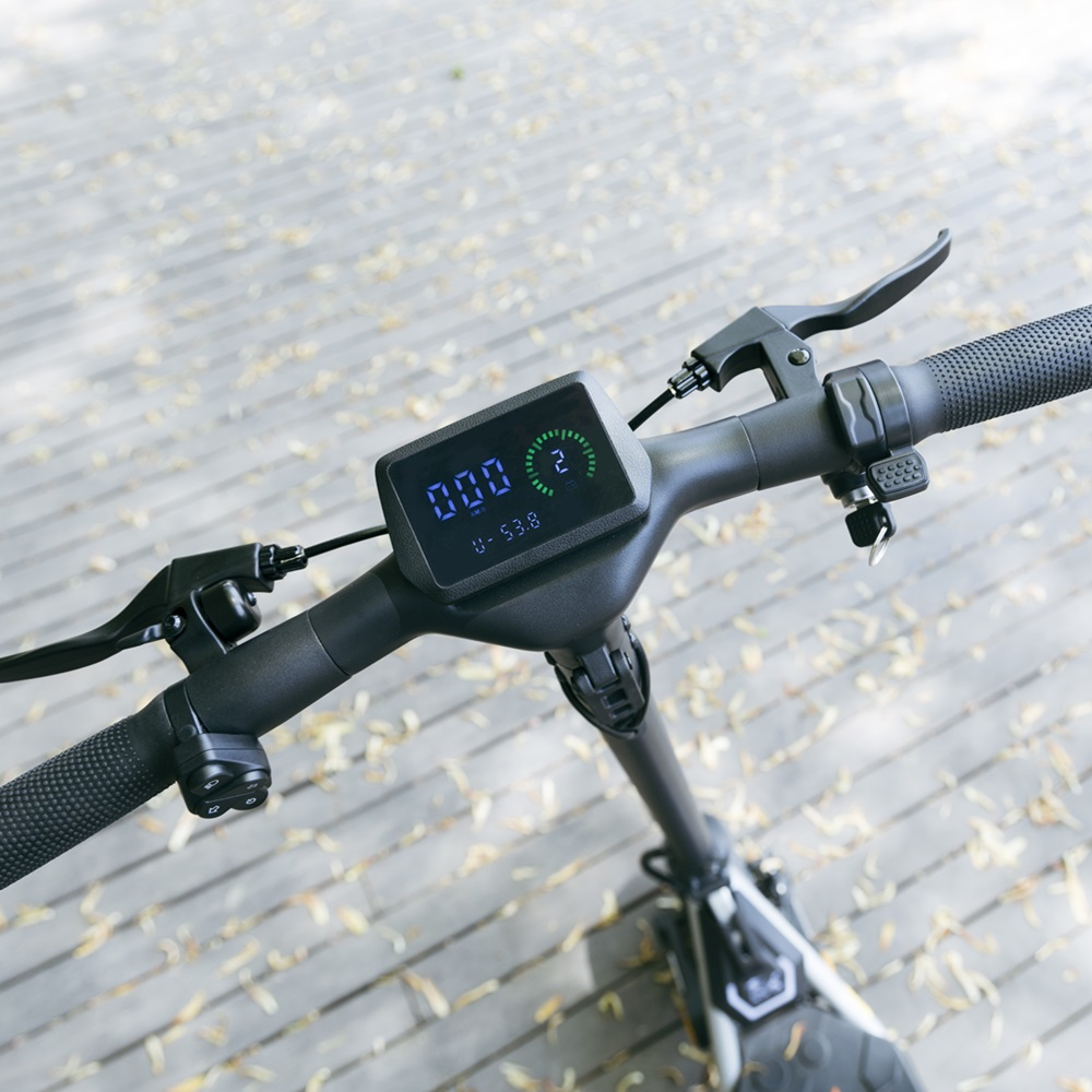 Un manubrio di scooter con un display che mostra la velocità e una luce verde.