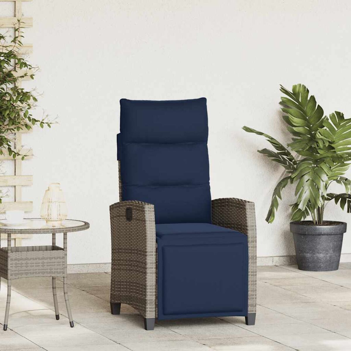 Sedia da patio esterna con cuscino blu navy e struttura in rattan contro un muro bianco.