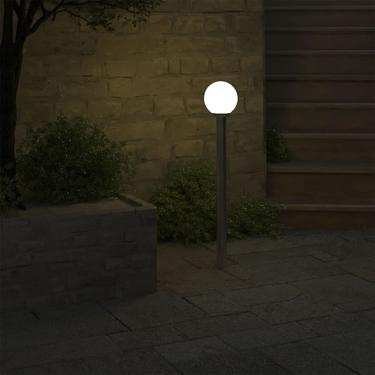 Una luce a globo bianco brillante su un palo argentato in un giardino di notte.