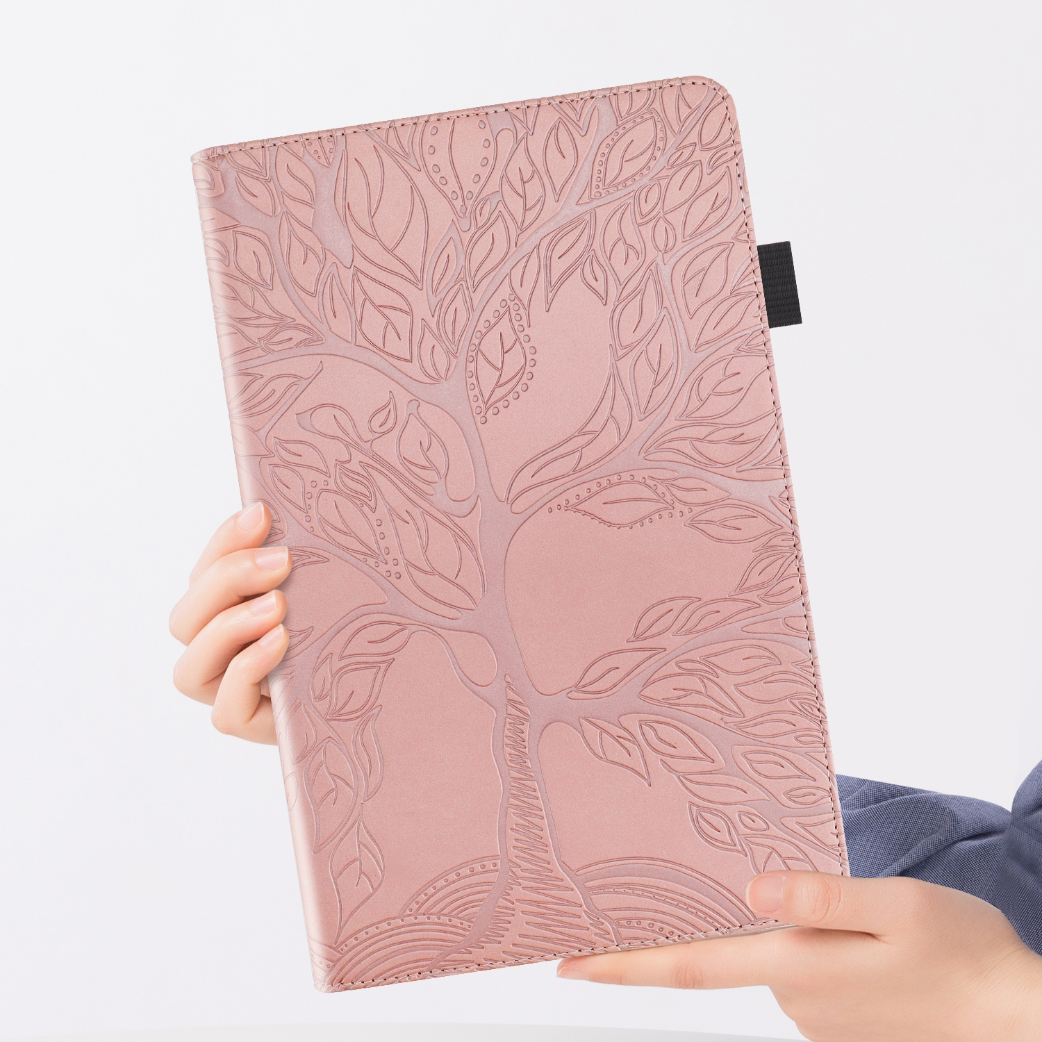 Rosa Tablethülle mit geprägtem Baumdesign. Eine Hand hält die Hülle vor weißem Hintergrund.