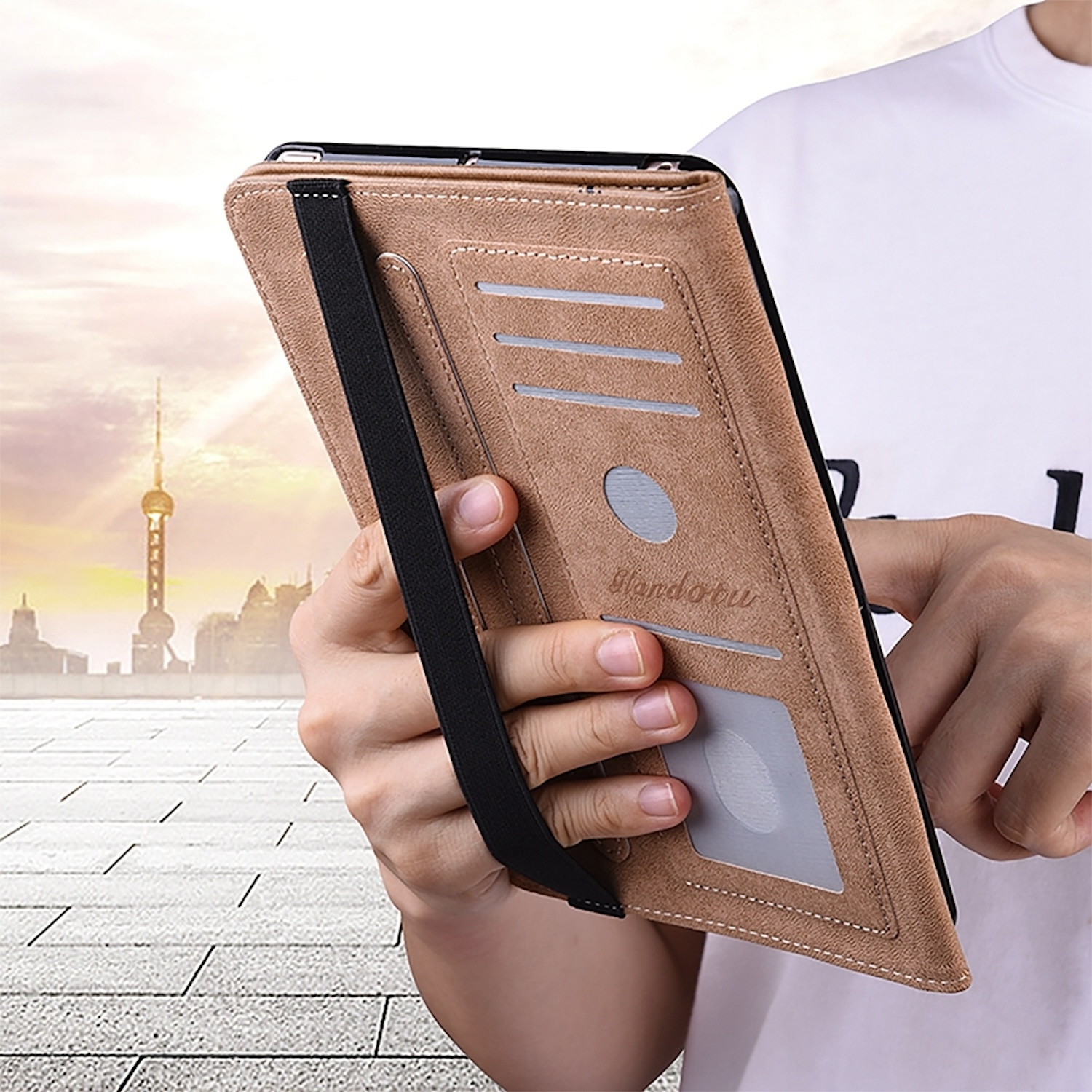 Tablet in einer braunen Lederhülle mit Kartenfächern und einer Hand, die es hält.