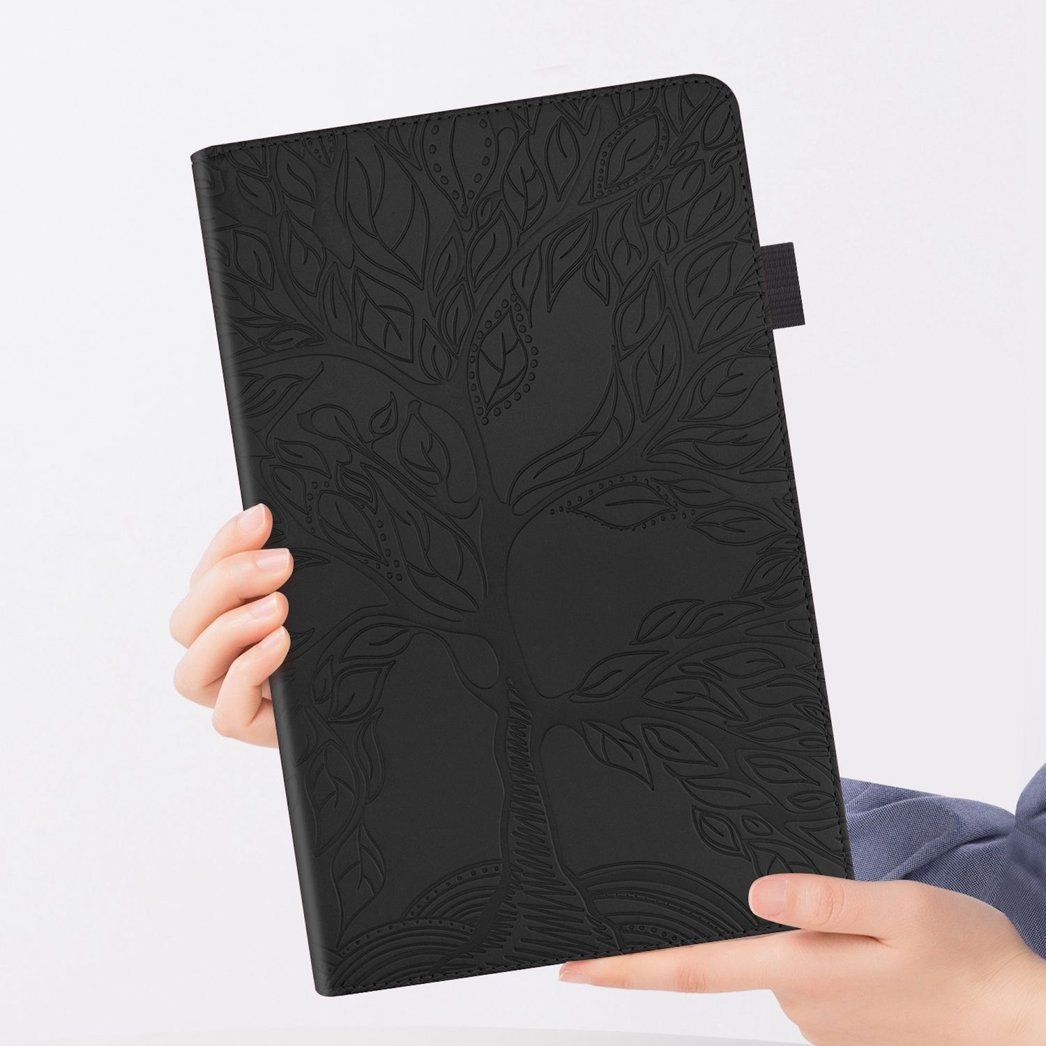 Una funda negra para tableta con un diseño de árbol en relieve, sostenida por manos. La funda está cerrada.