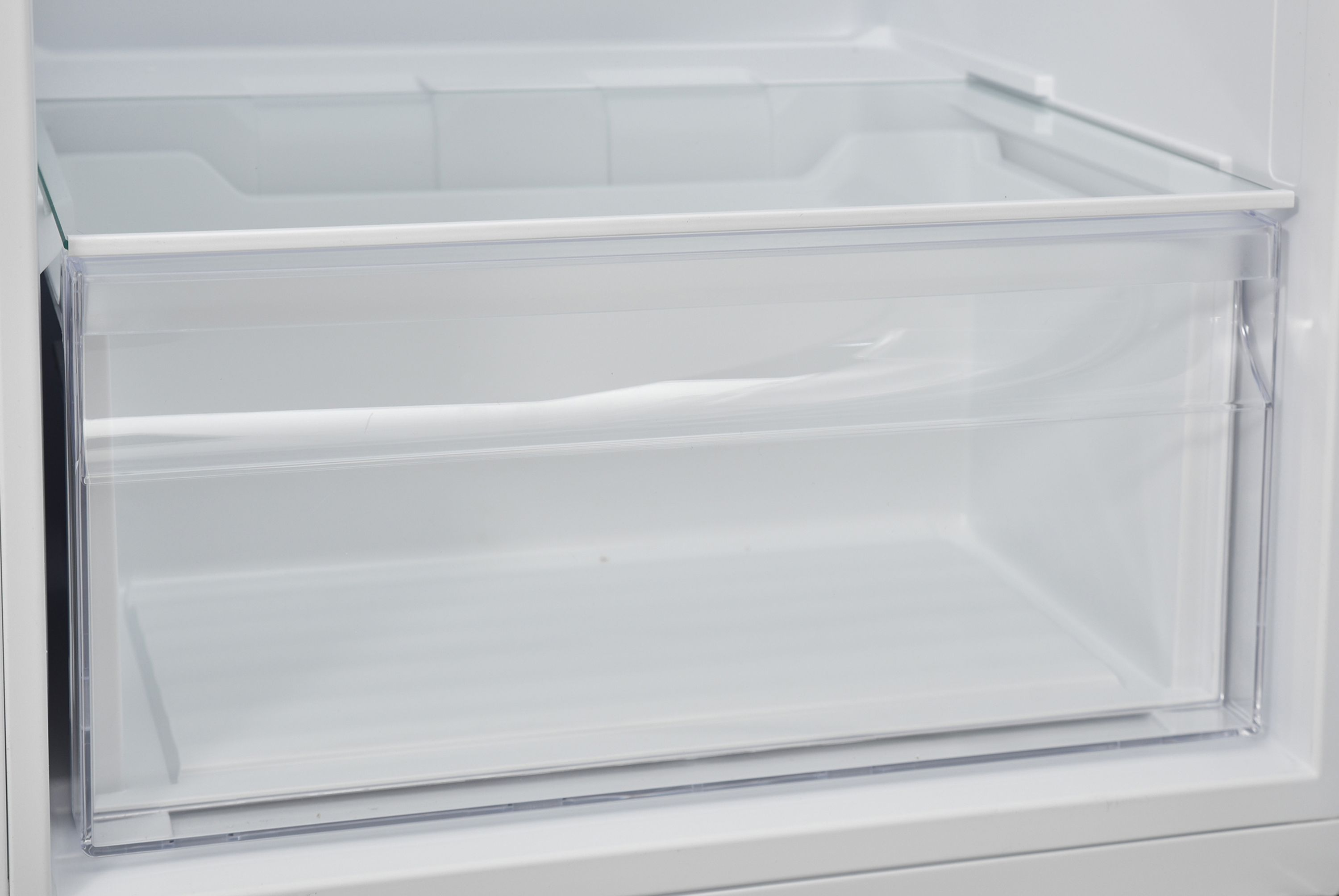 Offene, transparente Kühlschublade, Innenansicht mit weißem Hintergrund.