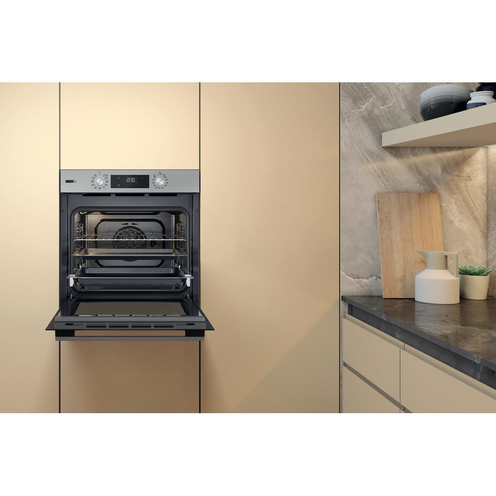Forno aperto in una cucina. Muri beige e un tagliere di legno di lato.