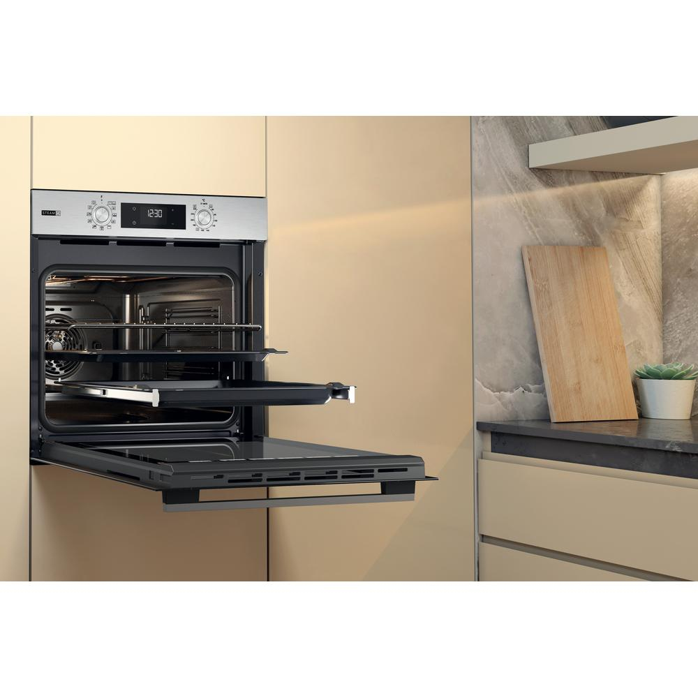 Forno con porta aperta, che mostra ripiani e comandi. Mobile beige ai lati.