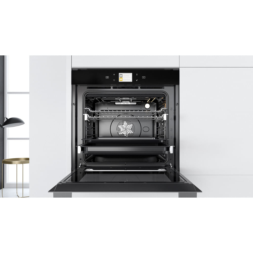 Forno moderno con porta aperta, interno visibile. Design nero e acciaio.