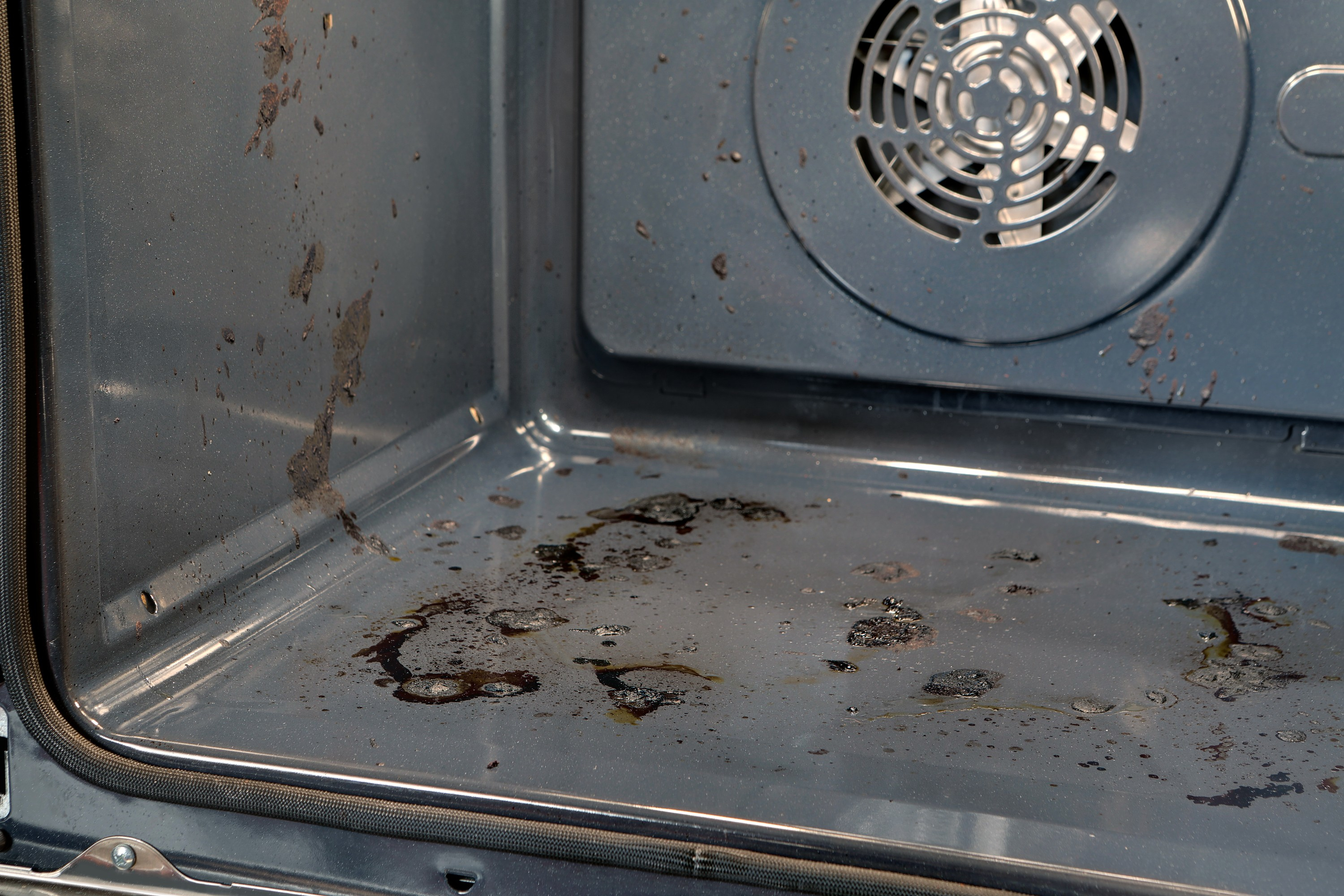 Interno del forno sporco con grasso e residui di cibo.