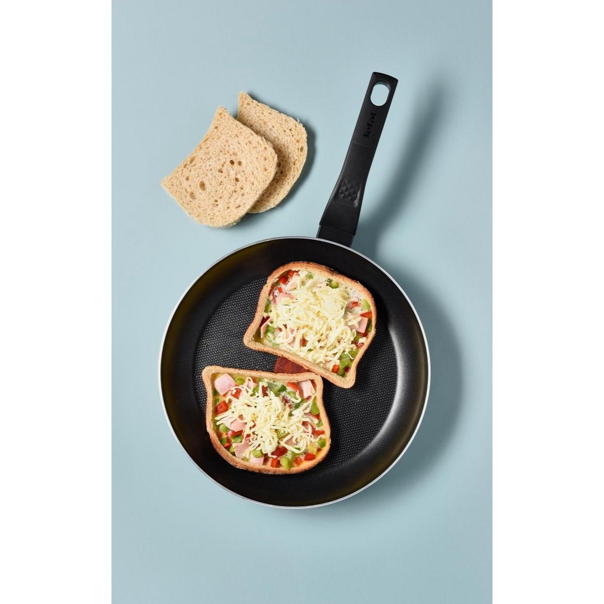 Toast pizza dans une poêle avec des tranches de pain, sur surface bleue.