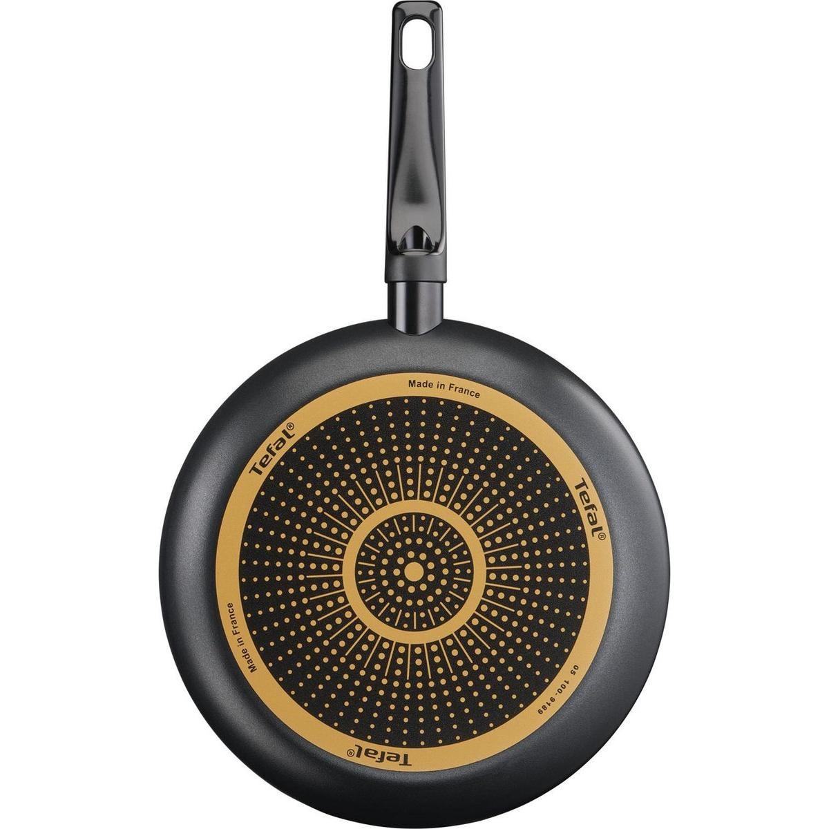 Une poêle Tefal noire vue d'en bas, montrant le fond avec le nom de la marque et la poignée.