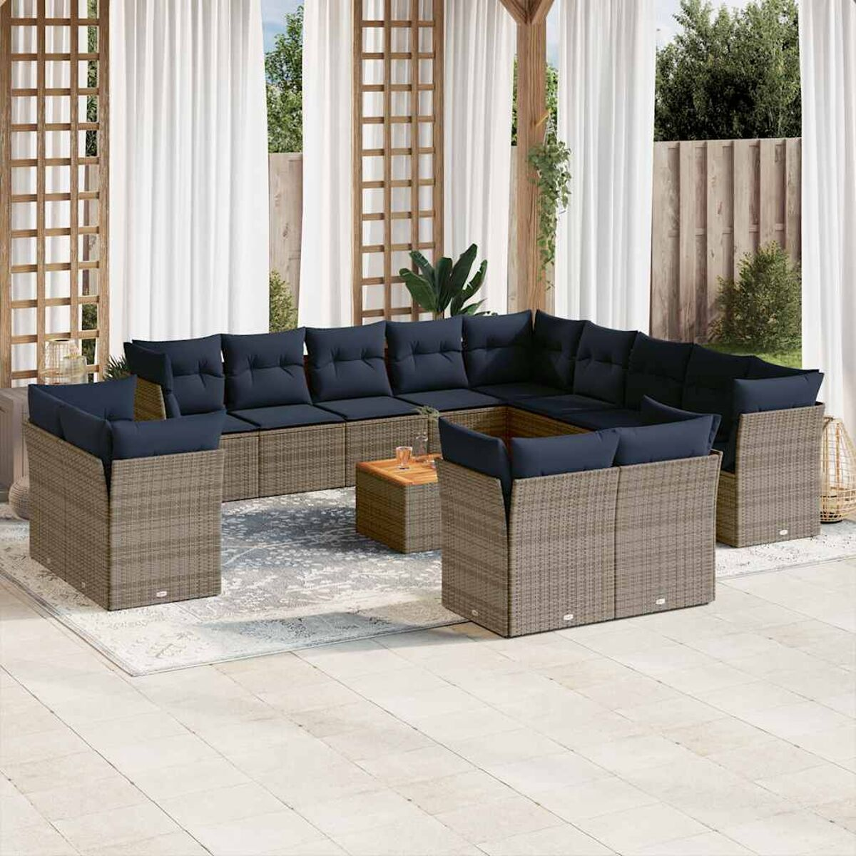 Un ampio divano componibile da esterno con cuscini blu e telai beige intrecciati, su un tappeto fantasia.