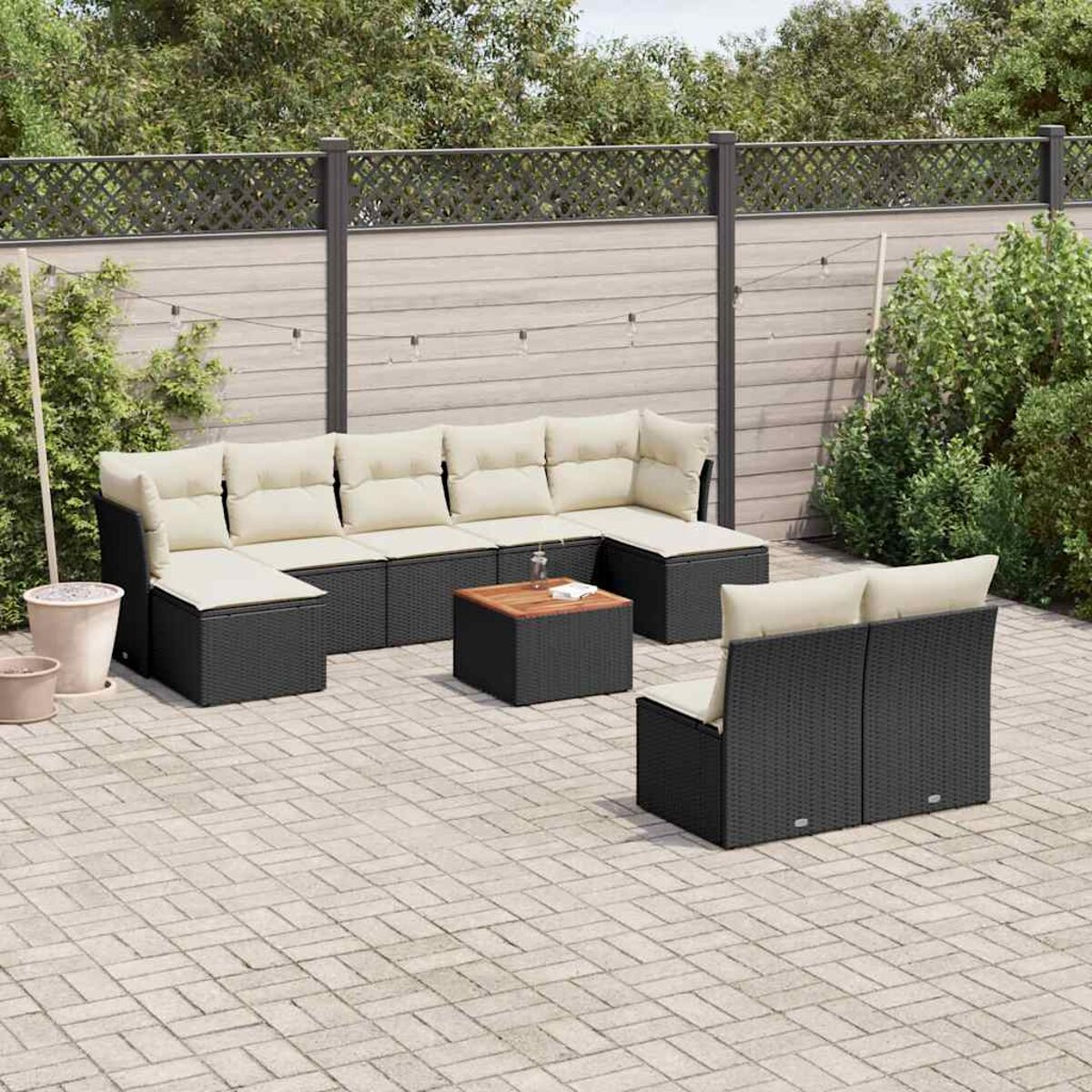 Ein schwarzes Terrassenset auf einer Ziegelterrasse. Es enthält ein Ecksofa, einen Tisch und einen Stuhl.