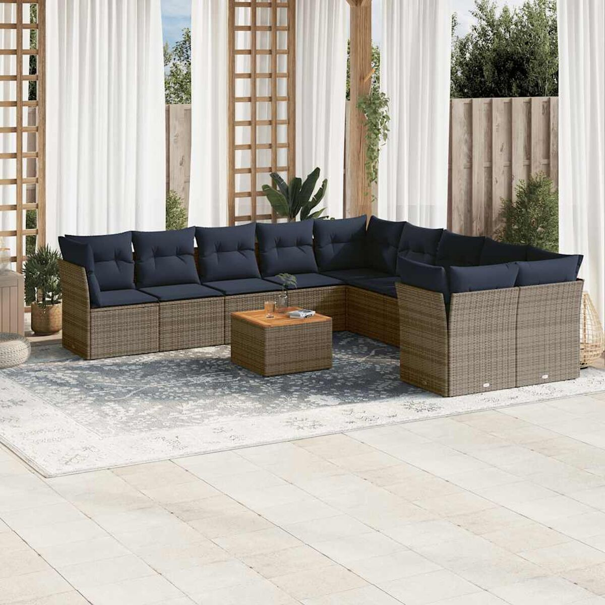 Set di mobili da esterno in rattan grigio con cuscini blu. Divano, tavolo e sedie. Tappeto e piante.