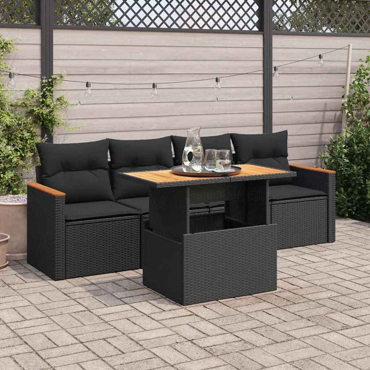 Set di mobili da esterno con tavolo e cuscini neri. Braccioli in legno. Patio.
