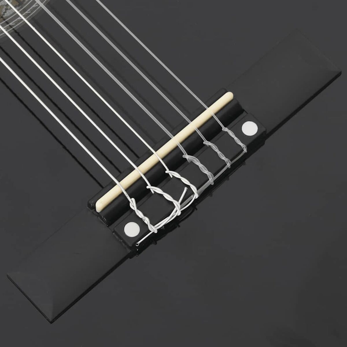 Nahaufnahme eines schwarzen Gitarrenstegs mit Saiten. Der Steg ist glänzend, und der Hintergrund ist dunkel.